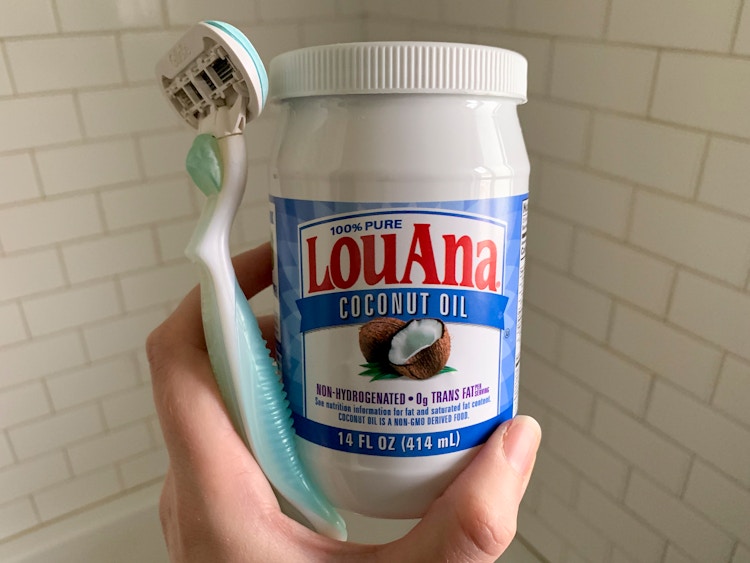 hand holding coconut oil and a women's razor