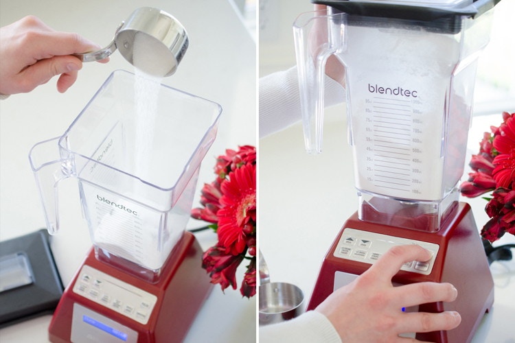 person-pouring-granulated-sugar-into-blender-next-to-a-person-pushing-buttons-on-a-blender