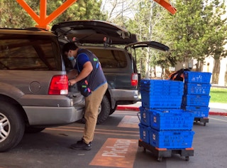 worker puts groceries in a shoppers trunk at walmart