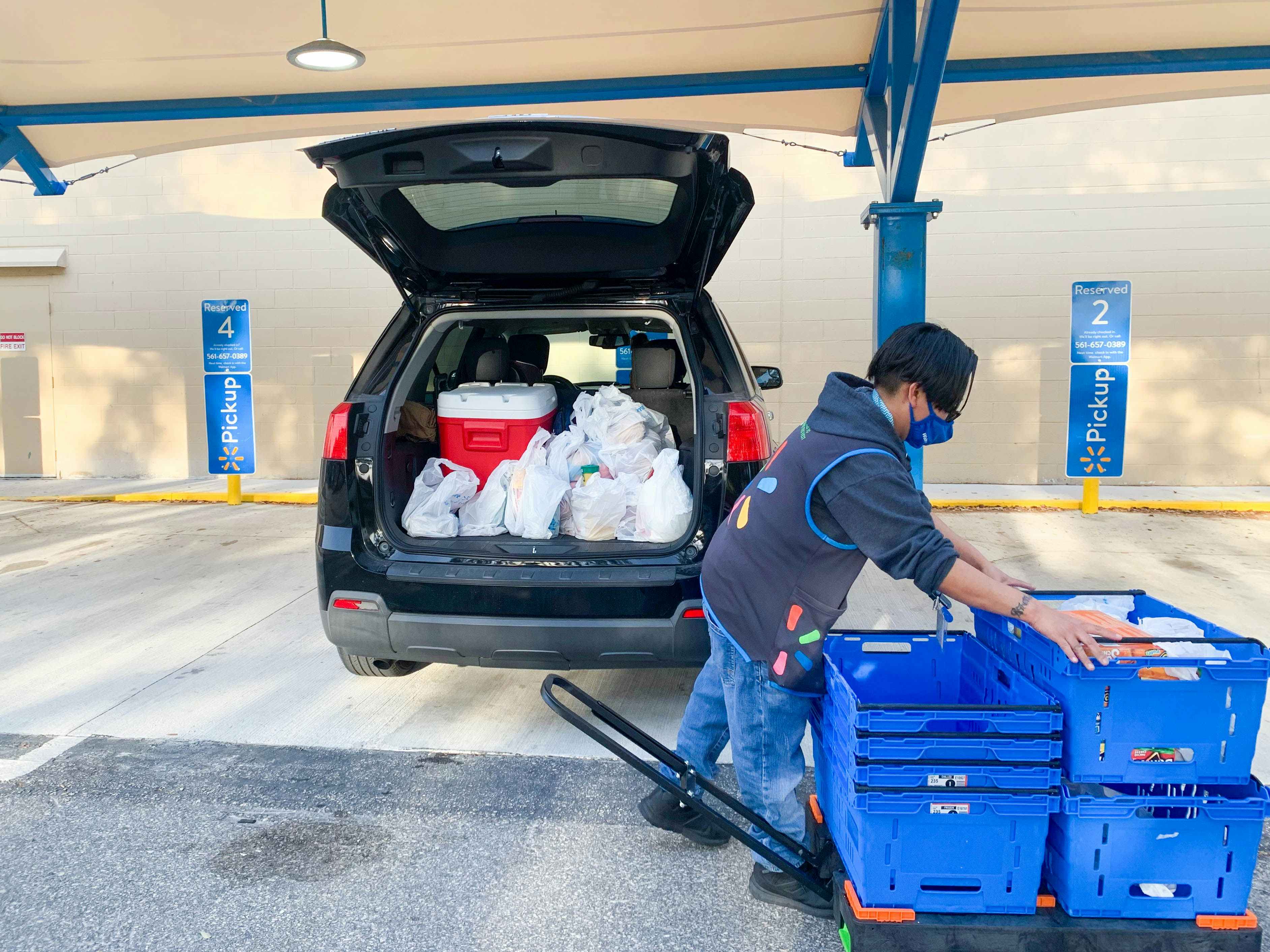 employee loading groceries in car at walmart pickup