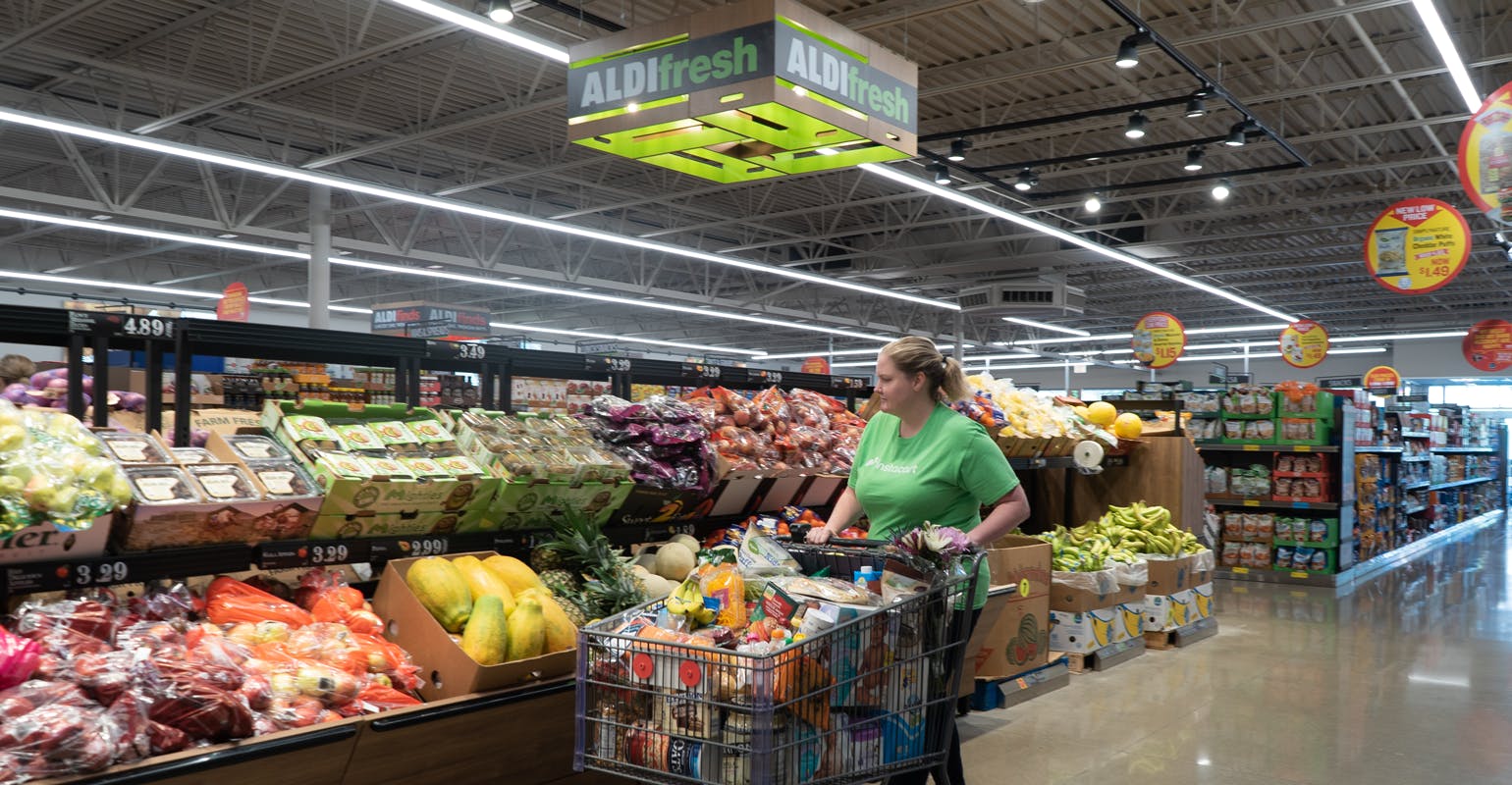 an instacart shopper peruses the produce at aldi