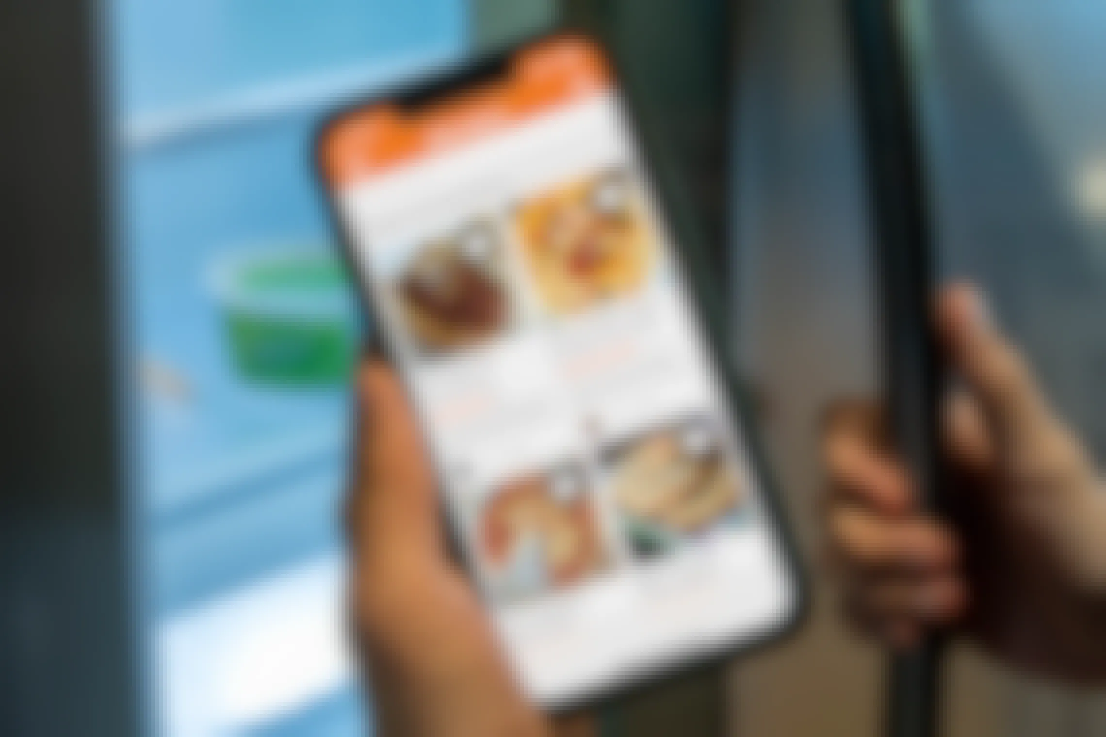 Allrecipes app on a cell phone held in front of a partly open refrigerator