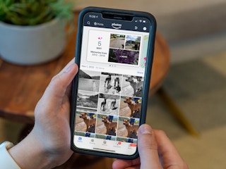 A person's hands holding a cell phone displaying the Amazon Photos app.
