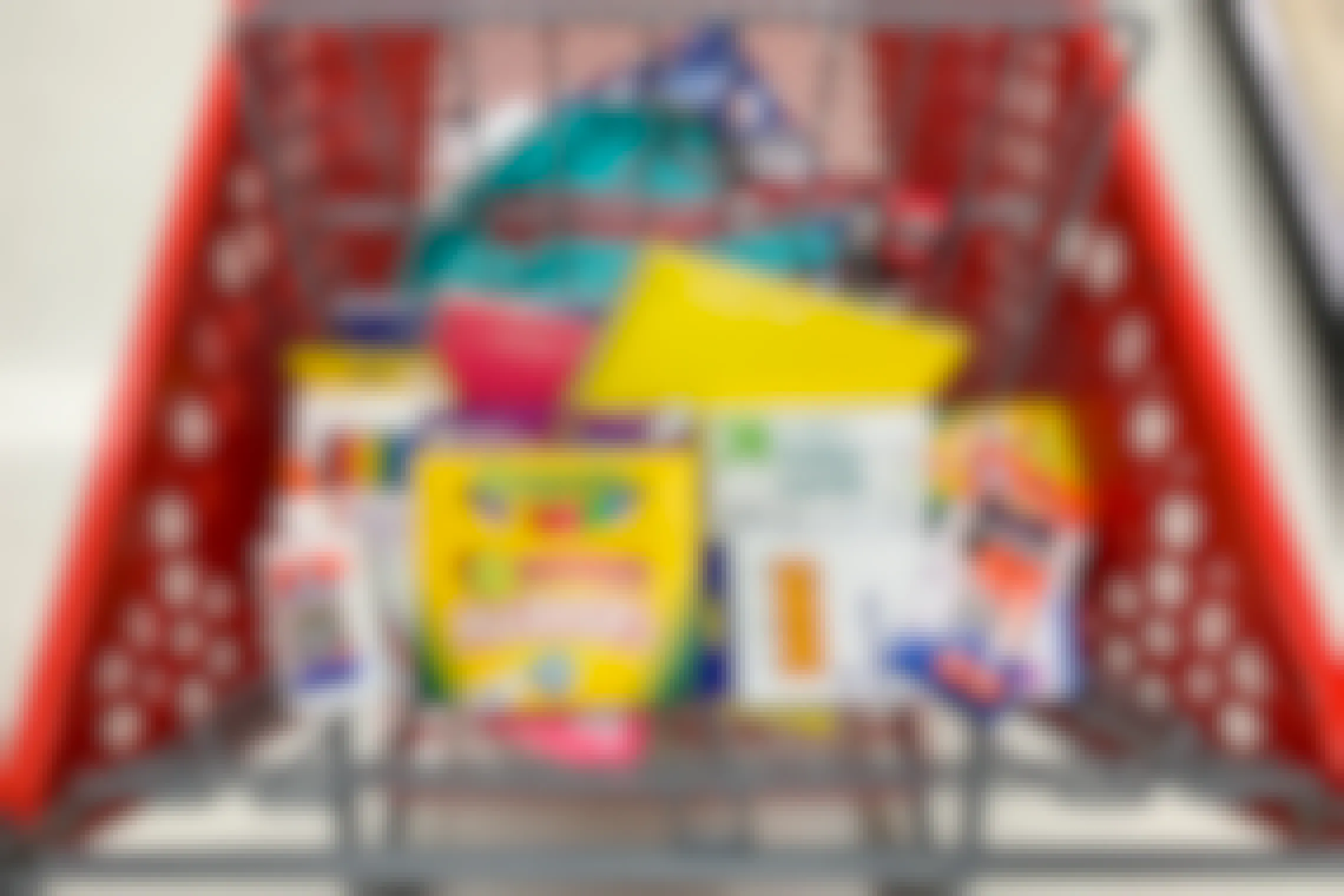 A Target shopping cart basket filled with school supplies such as Crayola markers, Elmer's glue, and Up&Up brand pencils, notebooks, and index cards.
