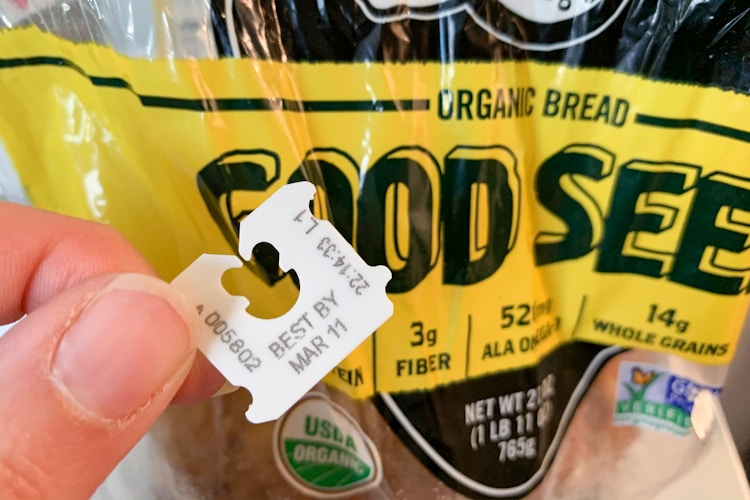 Person holding the bread tag on a bag that says, "best by Mar 11
