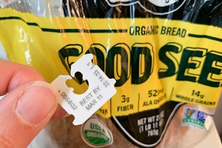 Person holding the bread tag on a bag that says, "best by Mar 11
