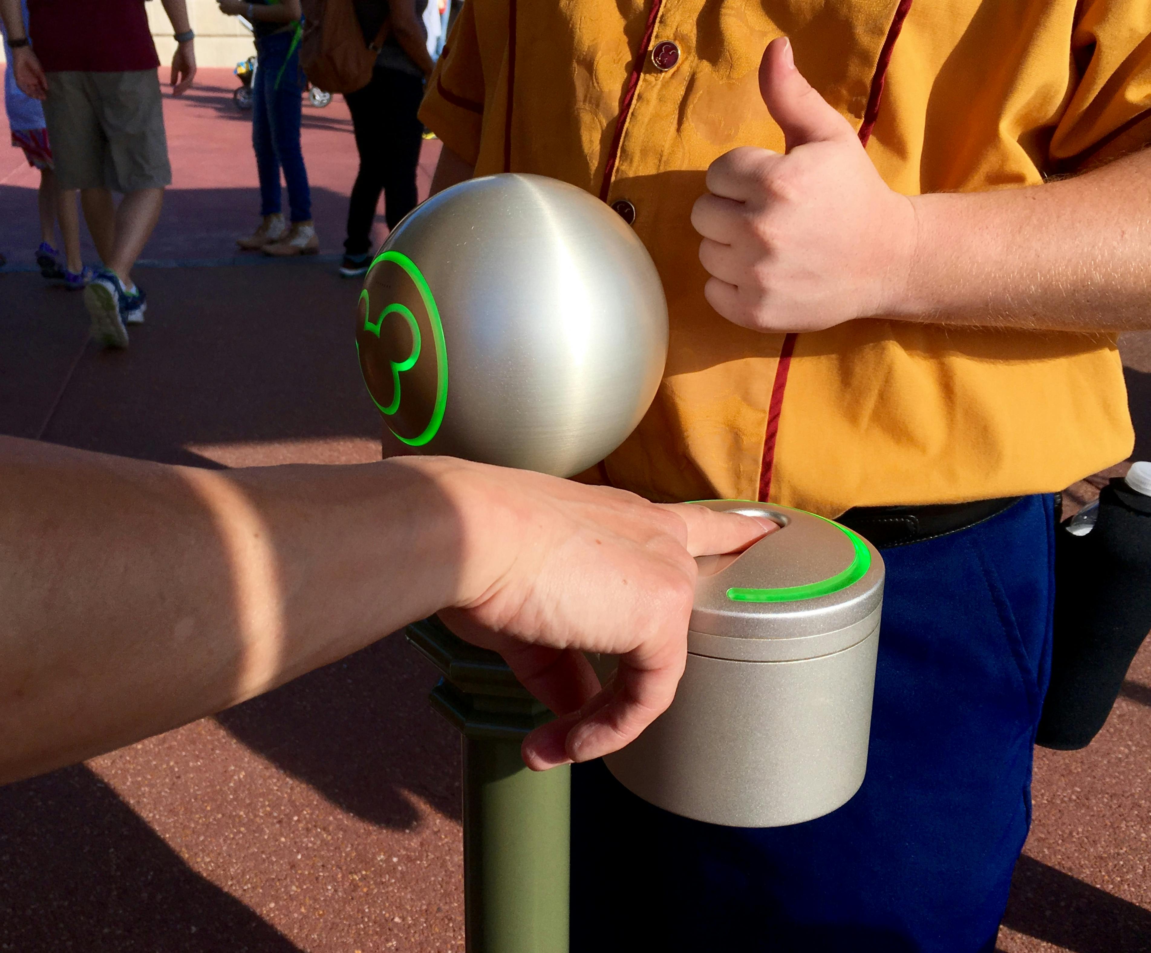 Man scanning finger at scanner in the park with Disney World employee giving a thumbs up