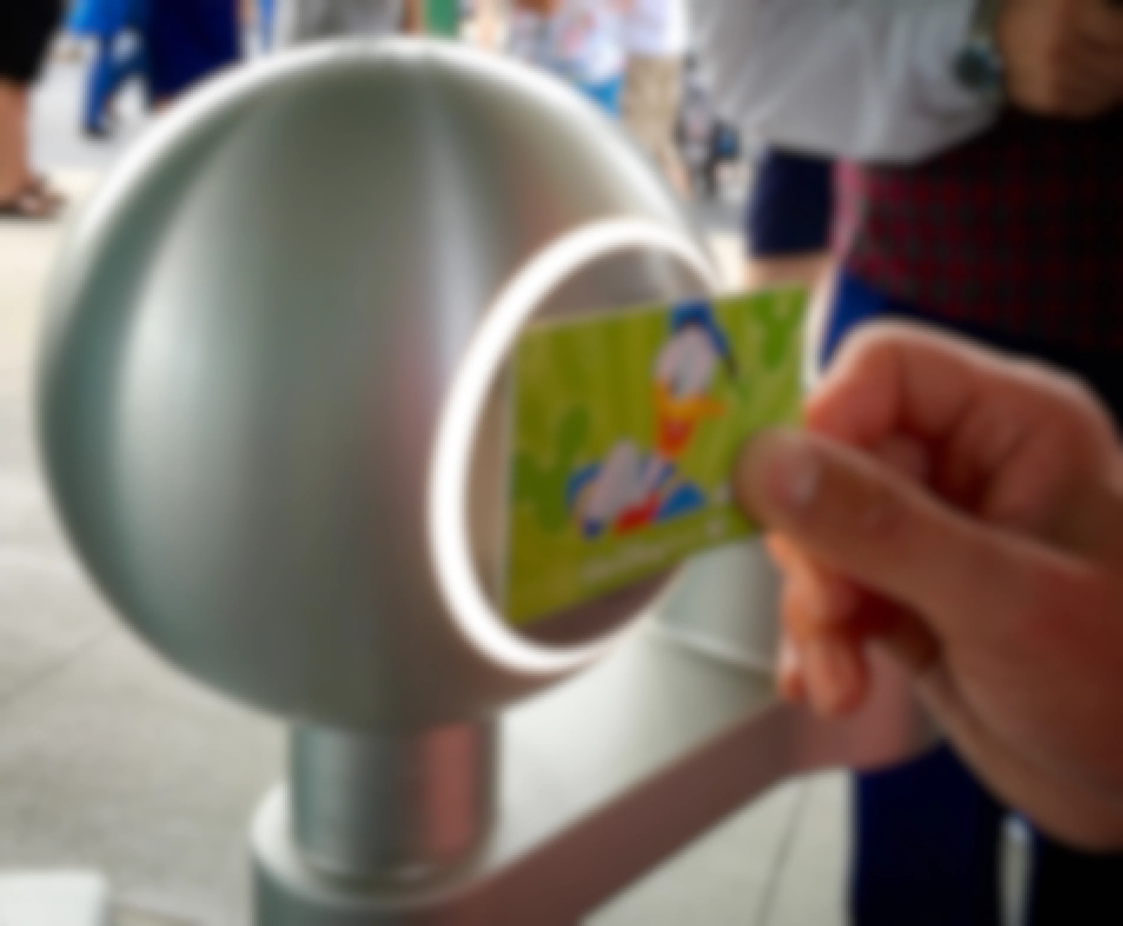 A person scanning their Disney pass card at a scanner in the Disney World park.