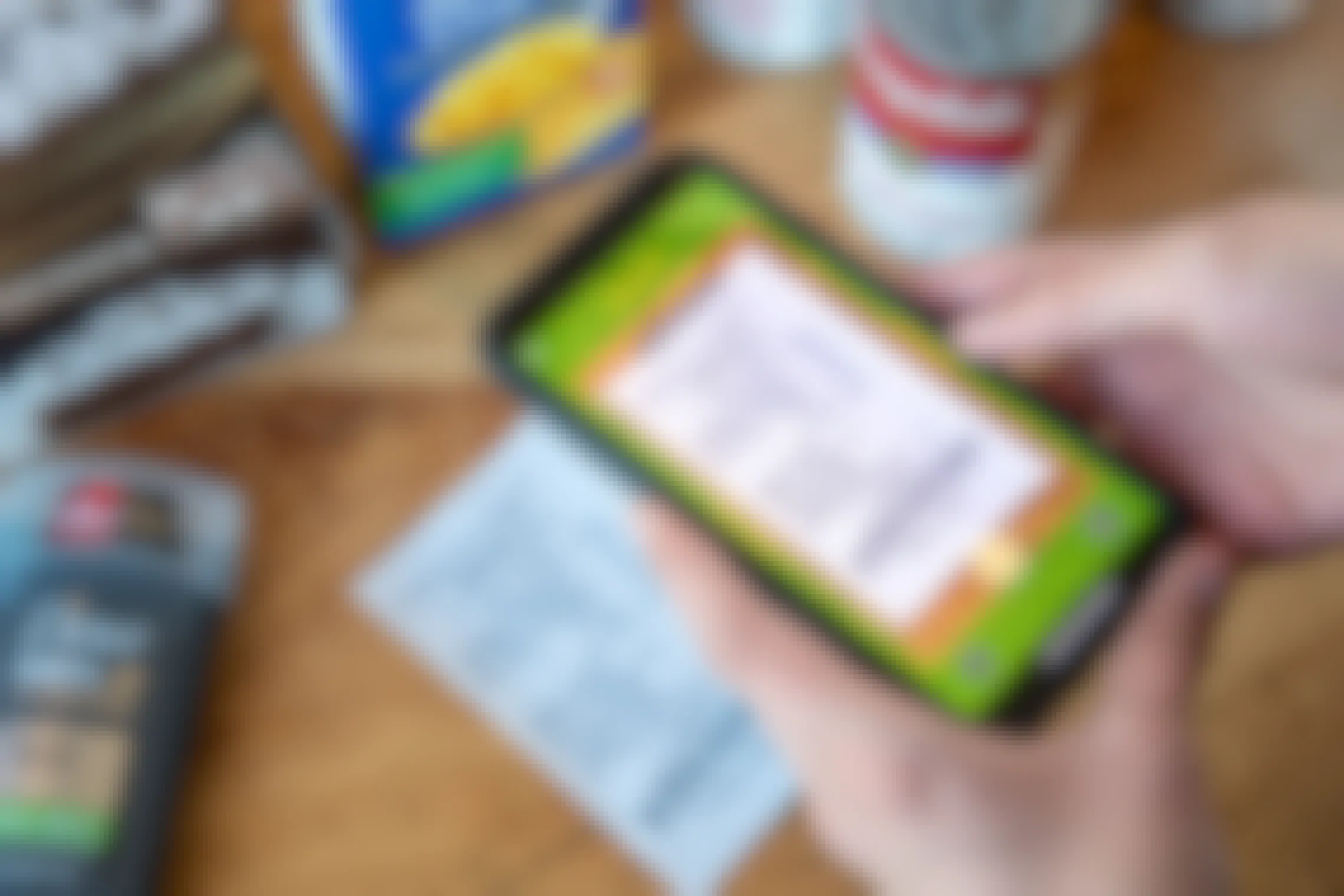 A person scanning a receipt into the Fetch Rewards app next to some grocery items on the table.