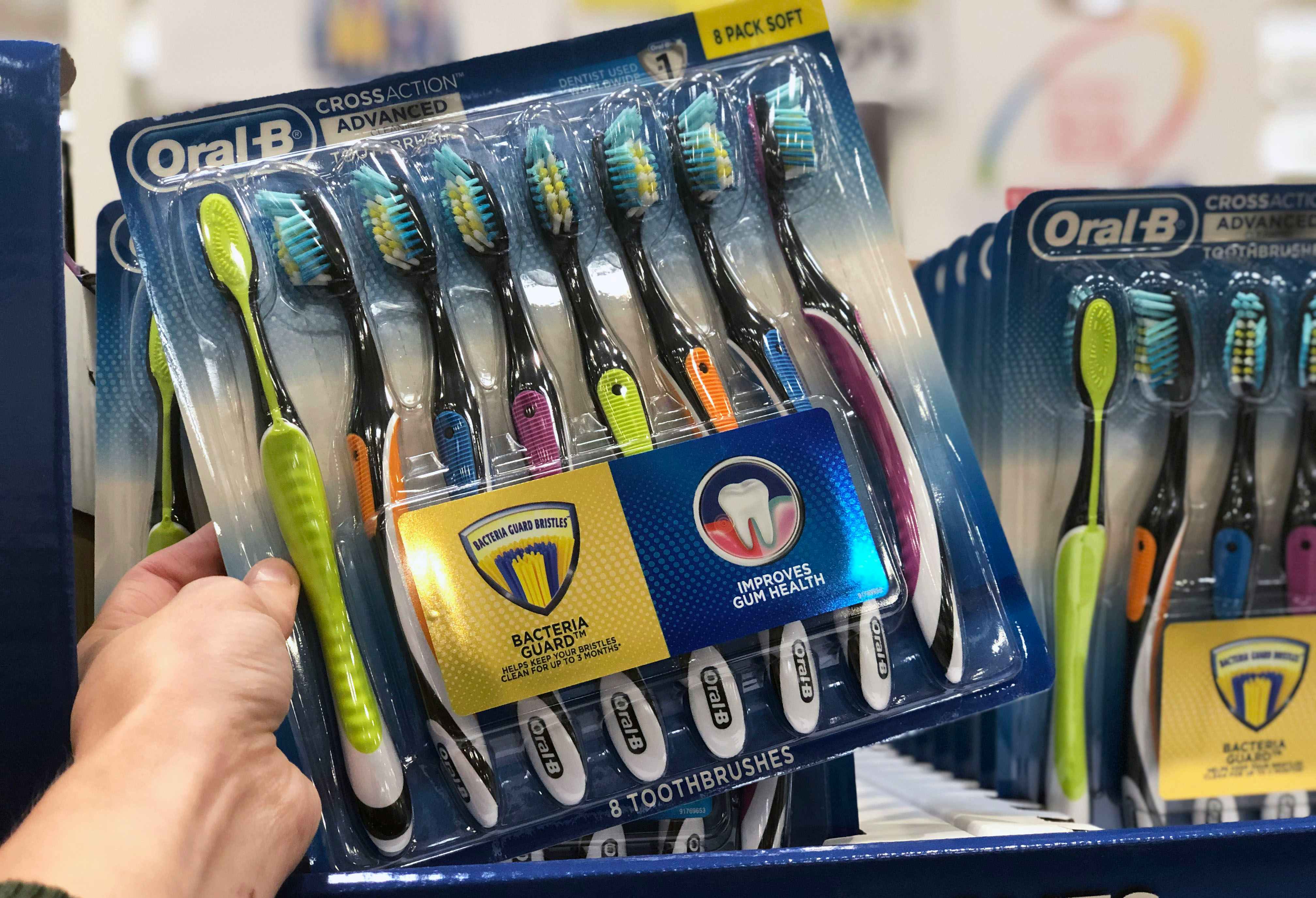 someone holding up a 8 pack of oral b toothbrushes