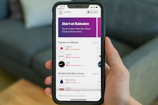 A person holding an iphone with the Rakuten app open on on it.