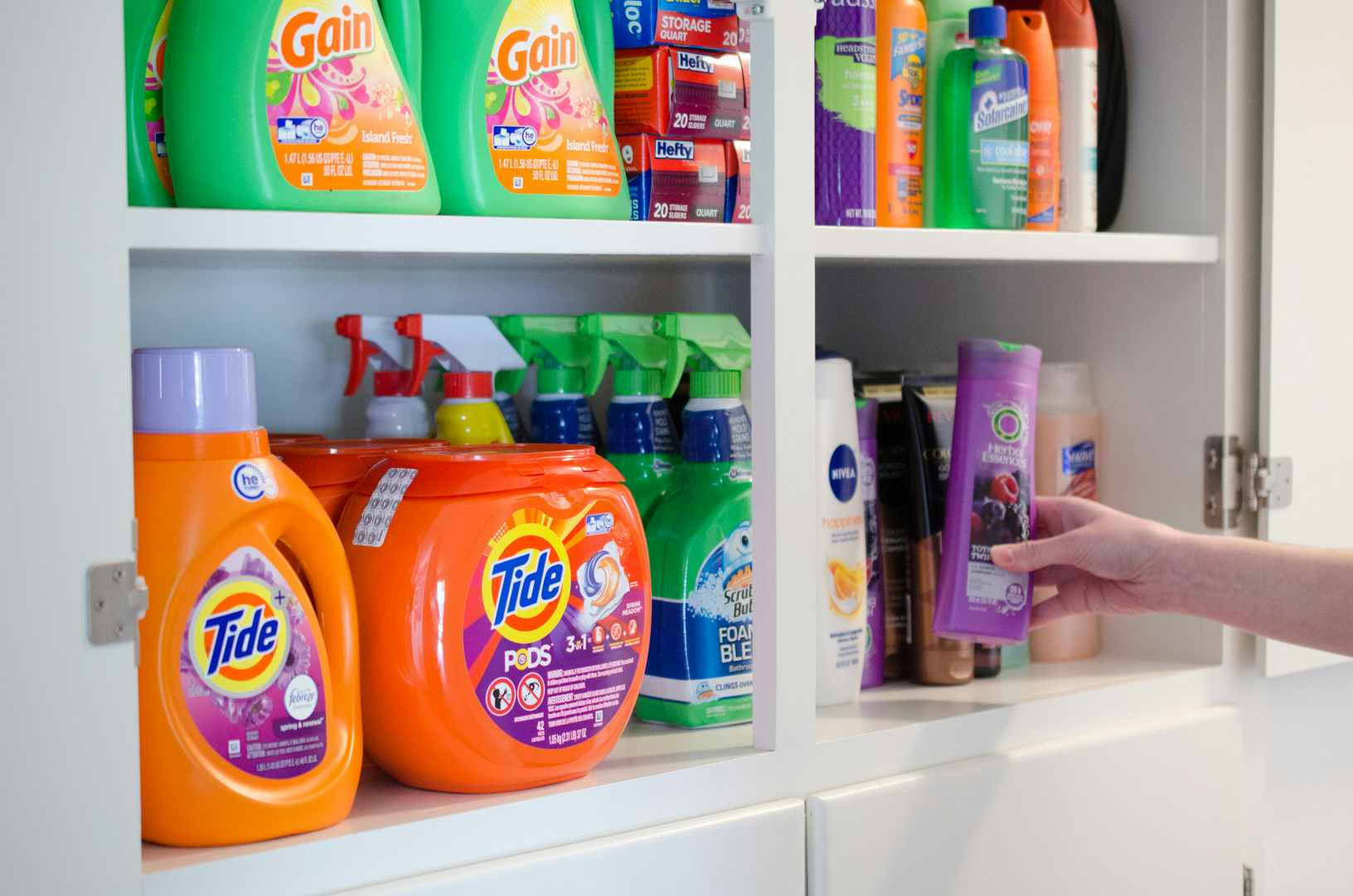 Cleaning supplies, laundry detergent, personal care items, stockpiled into a cupboard.