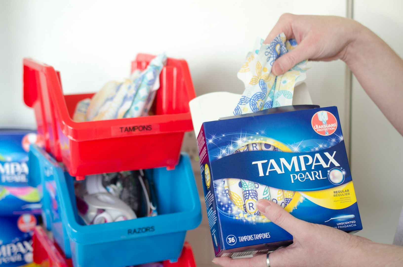 A woman removing tampons from the packaging and storing them in plastic bins.