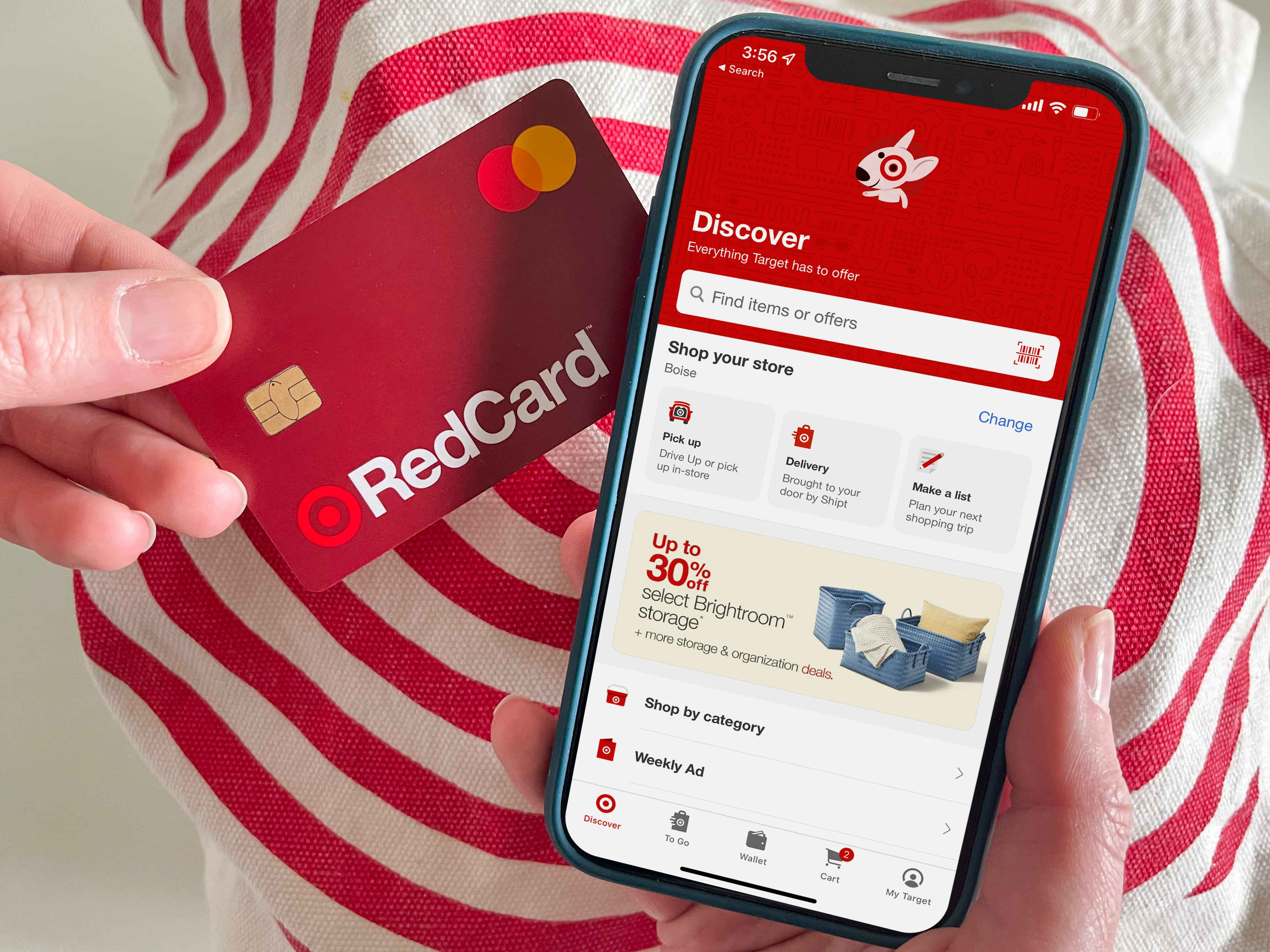 A target red card held next to a cell phone with the Target app open on the screen