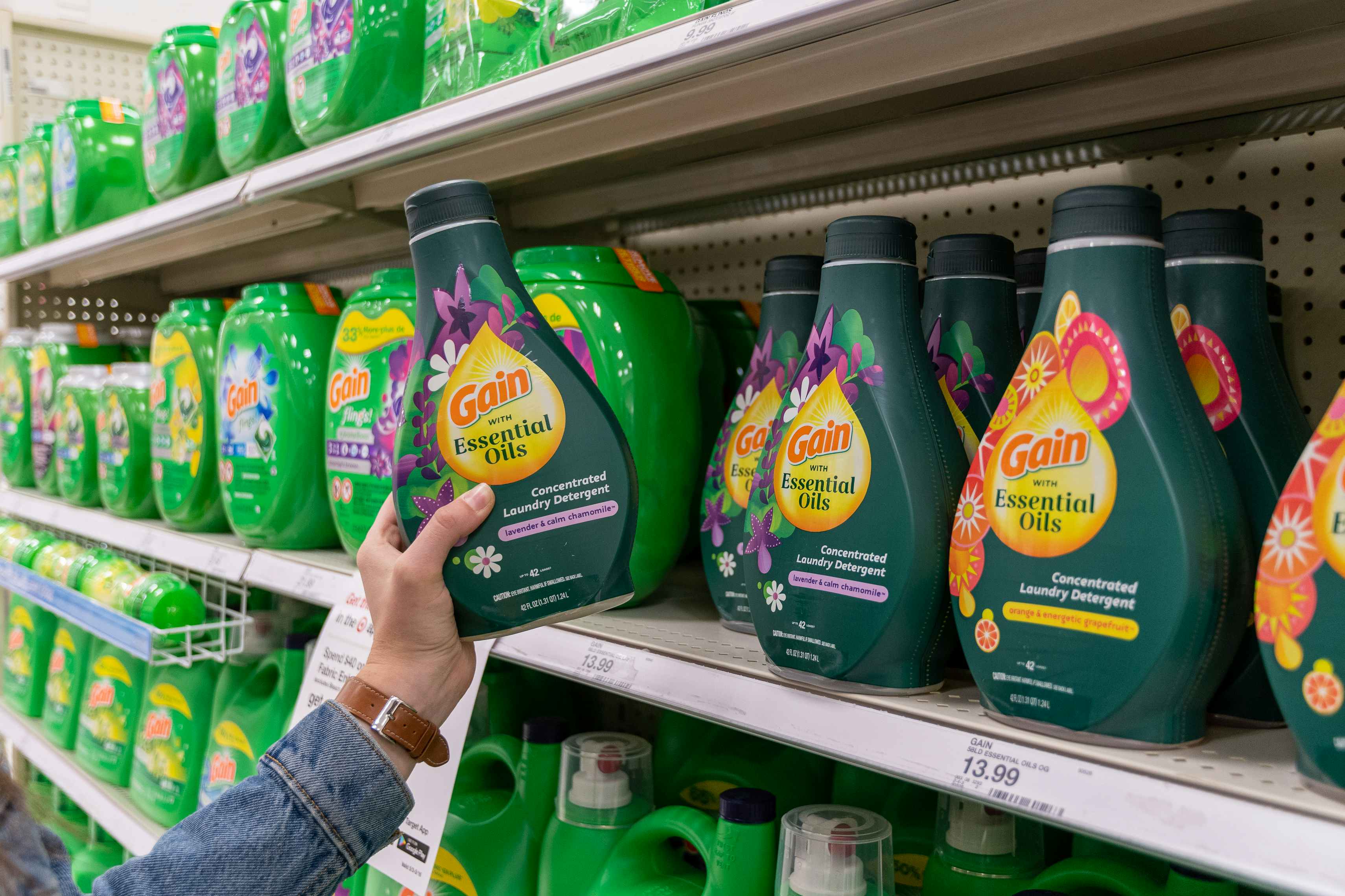 Woman pulling gain laundry detergent from shelf inside target.