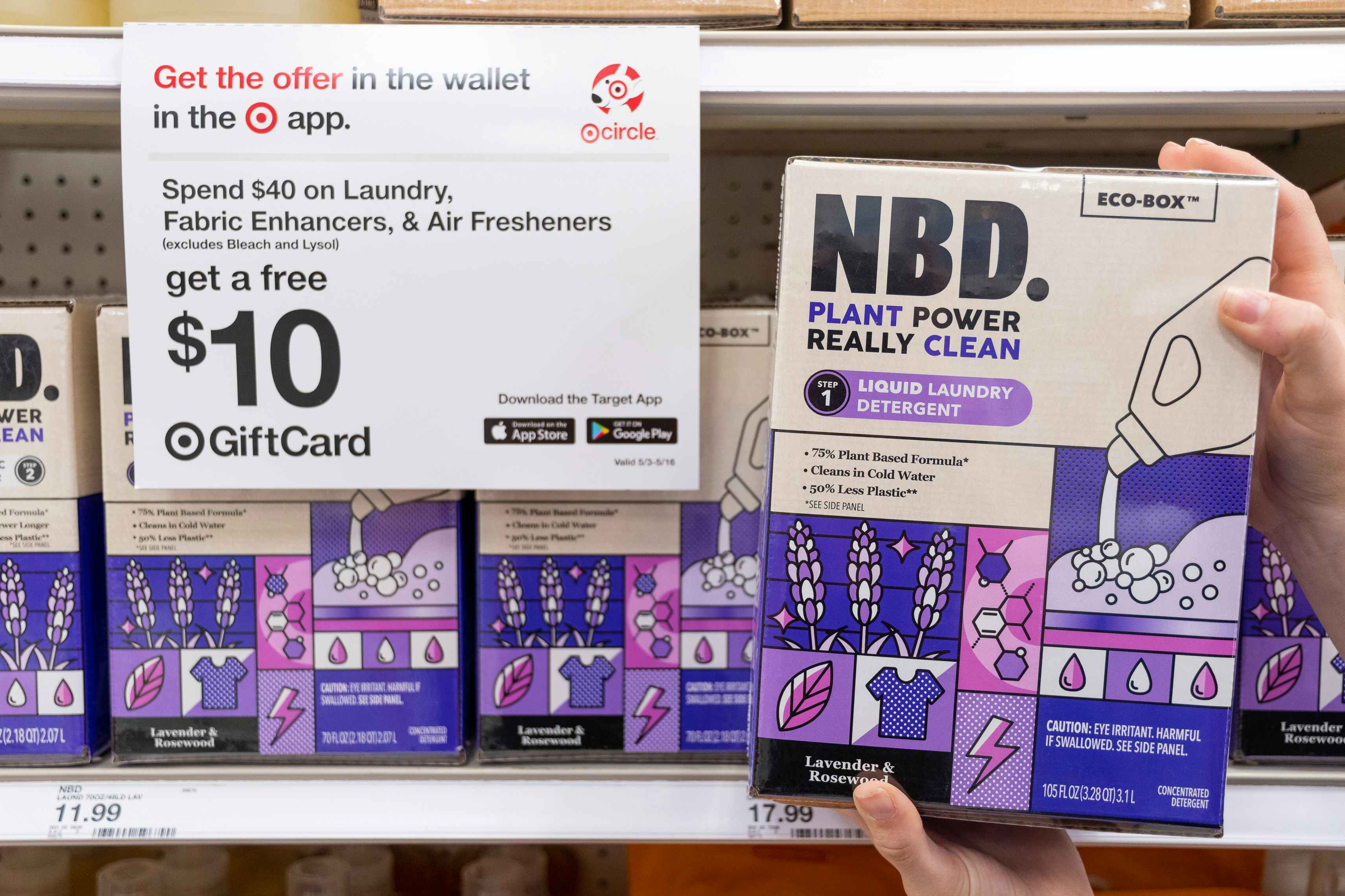 A person holding up a box of NBD laundry detergent next to a sign for a free $10 gift card with a $40 laundry purchase