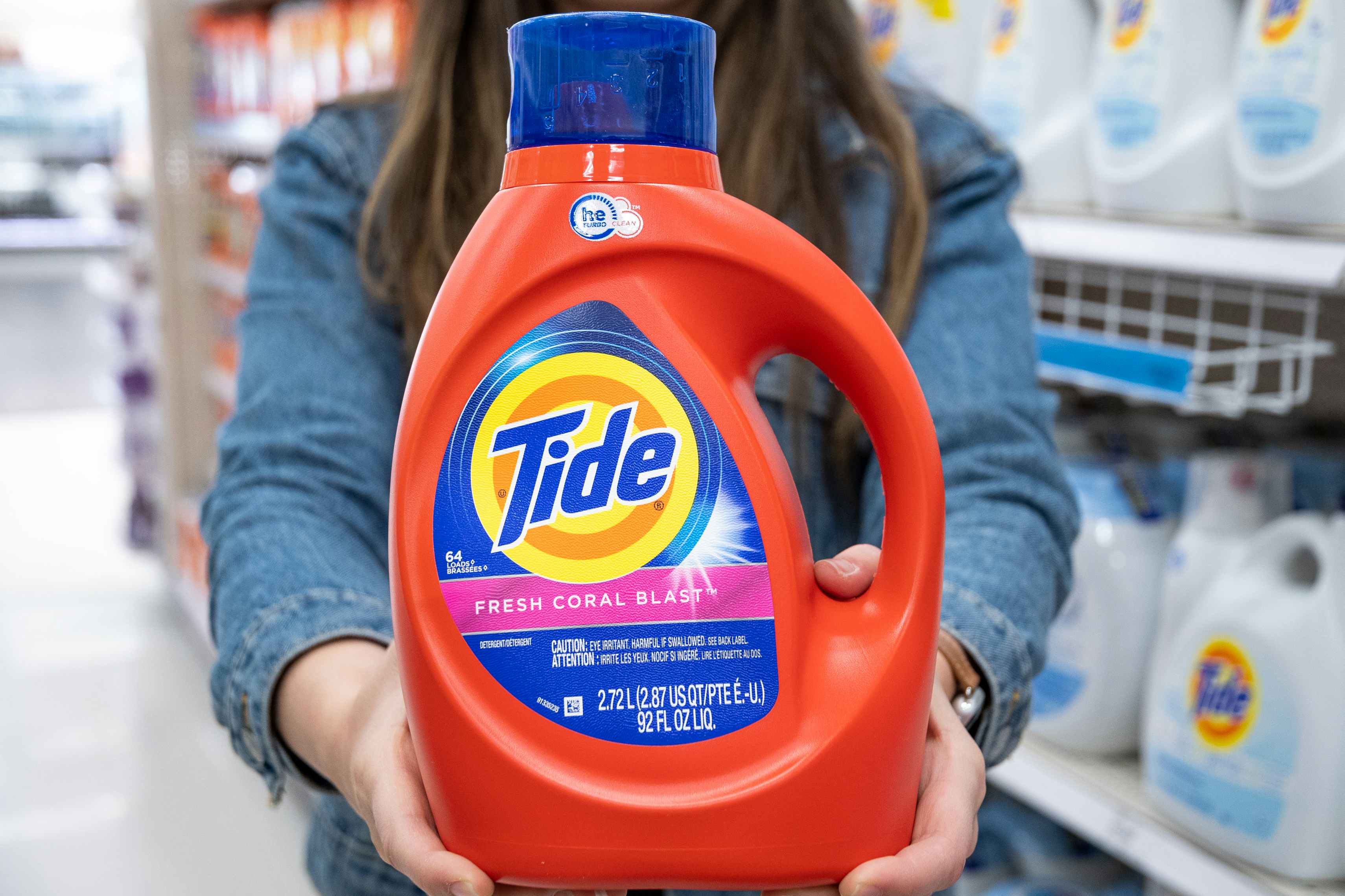 Woman holding out a bottle of Tide liquid detergent.