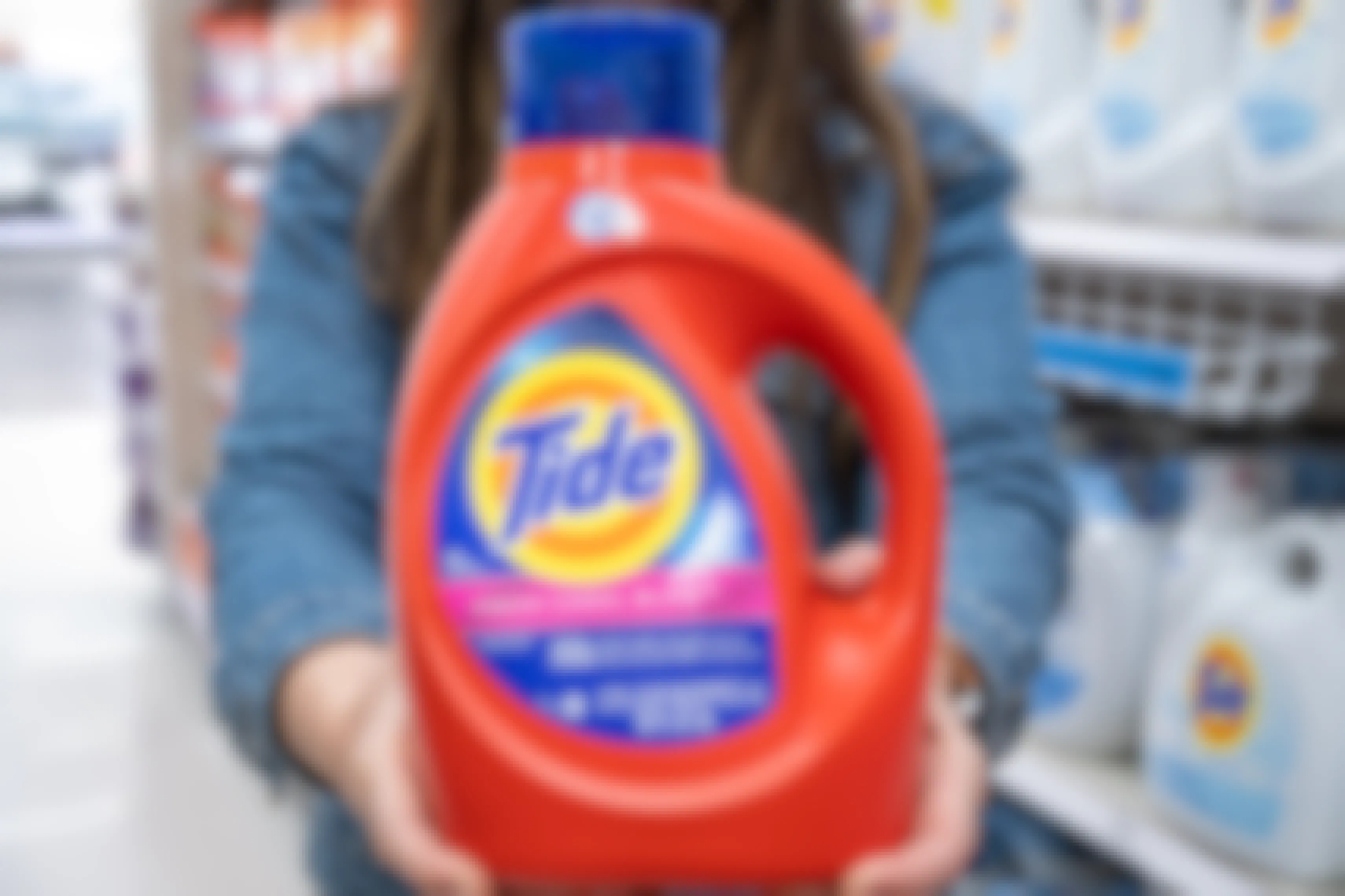 Woman holding out a bottle of Tide liquid detergent.