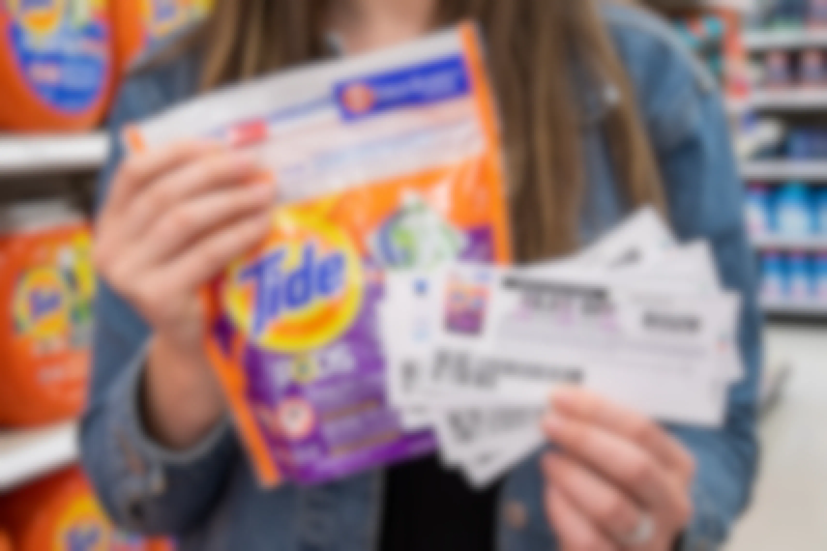 A woman holding a pack of tide Pods with printed manufacture coupons in hand.