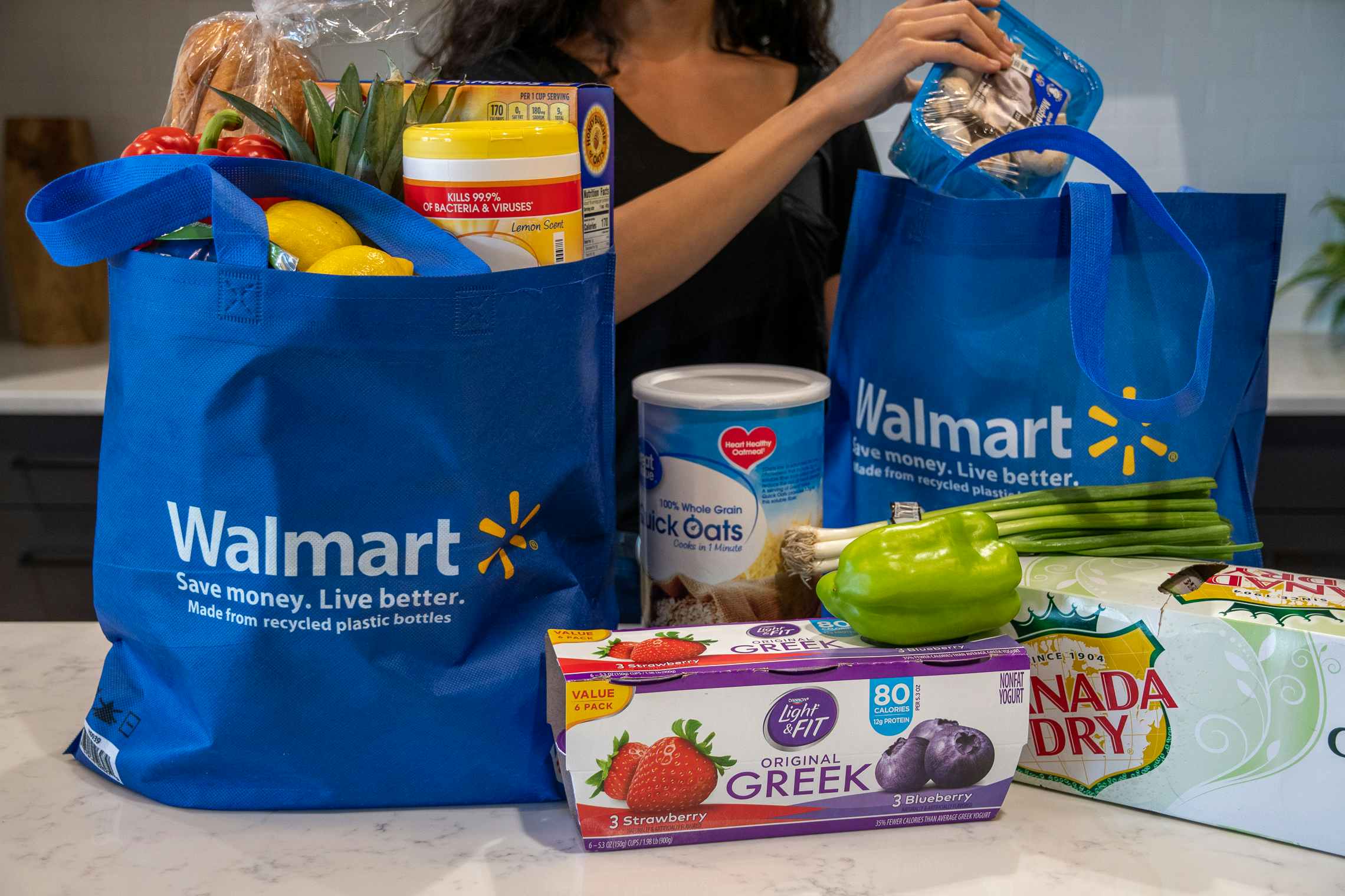 A woman pulling groceries out of Walmart reusable grocery bags.