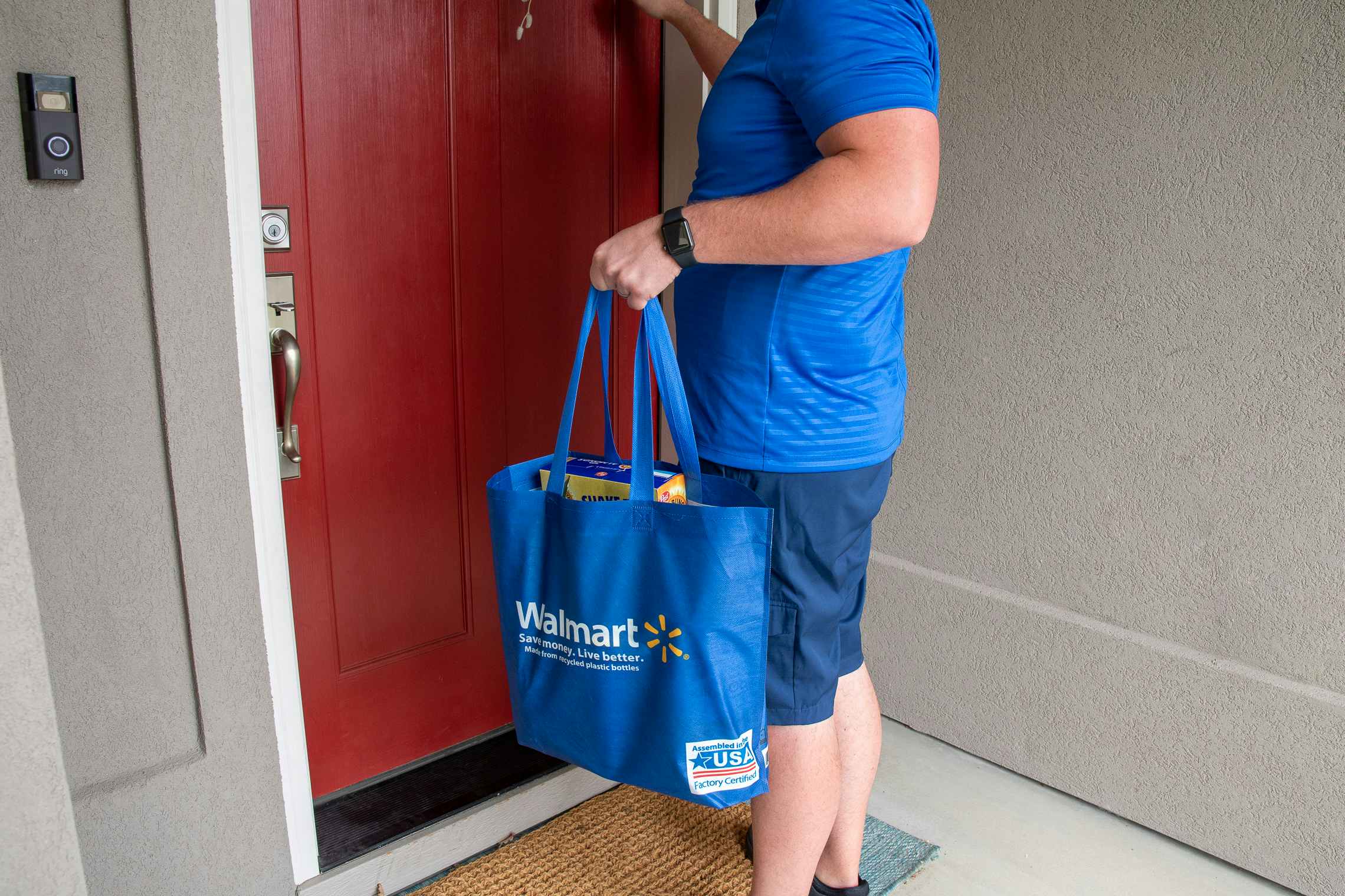 A walmart delivery employee knocking on a front door.