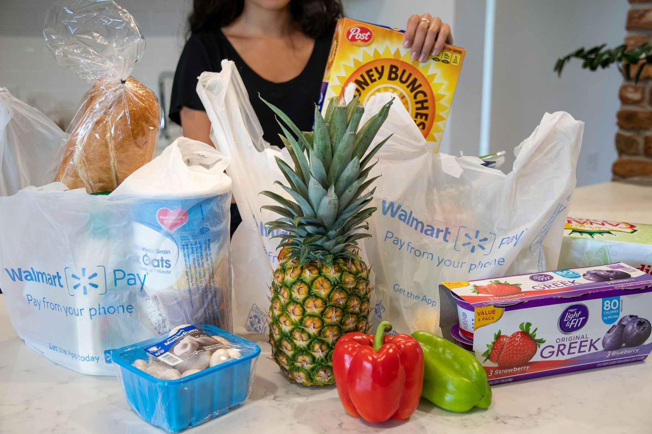 A woman pulling groceries from plastic walmart grocery bags.