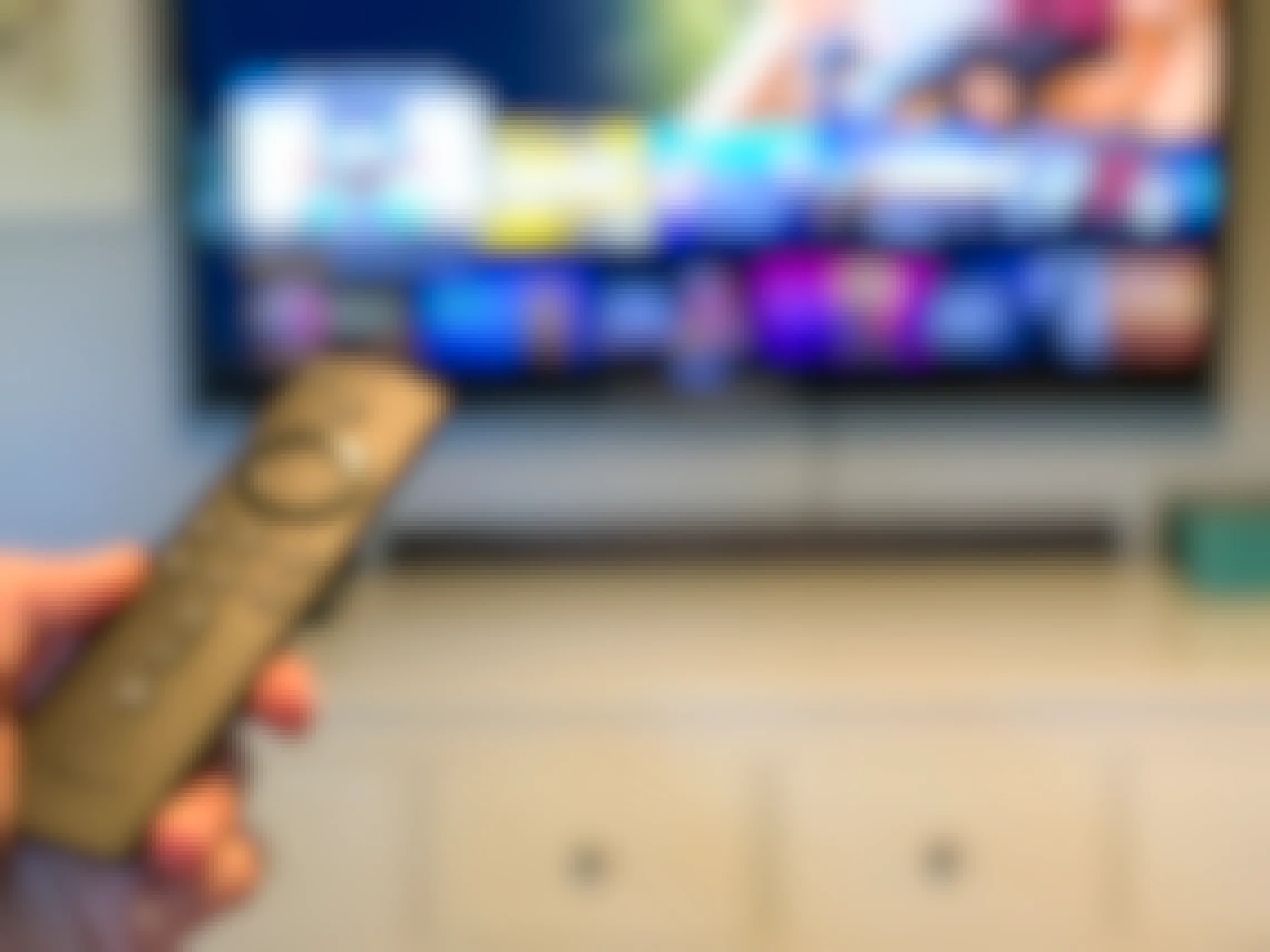 Amazon fire tv stick pointed at a tv with programs out of focus in the background.