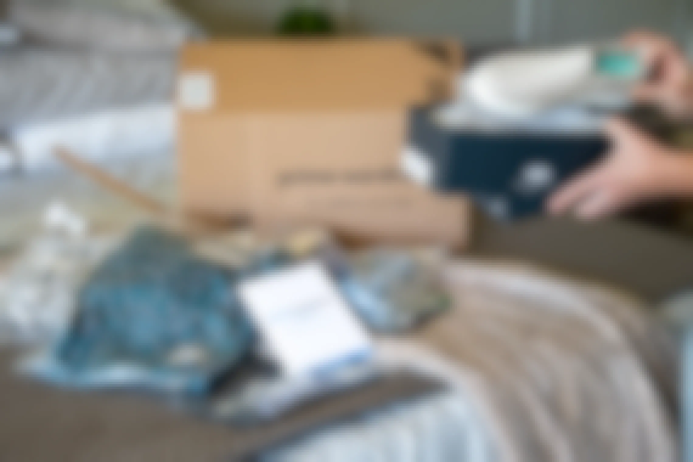 A woman looking at a pair of shoes ordered from Amazon Prime wardrobe with items from an order box in the background. 