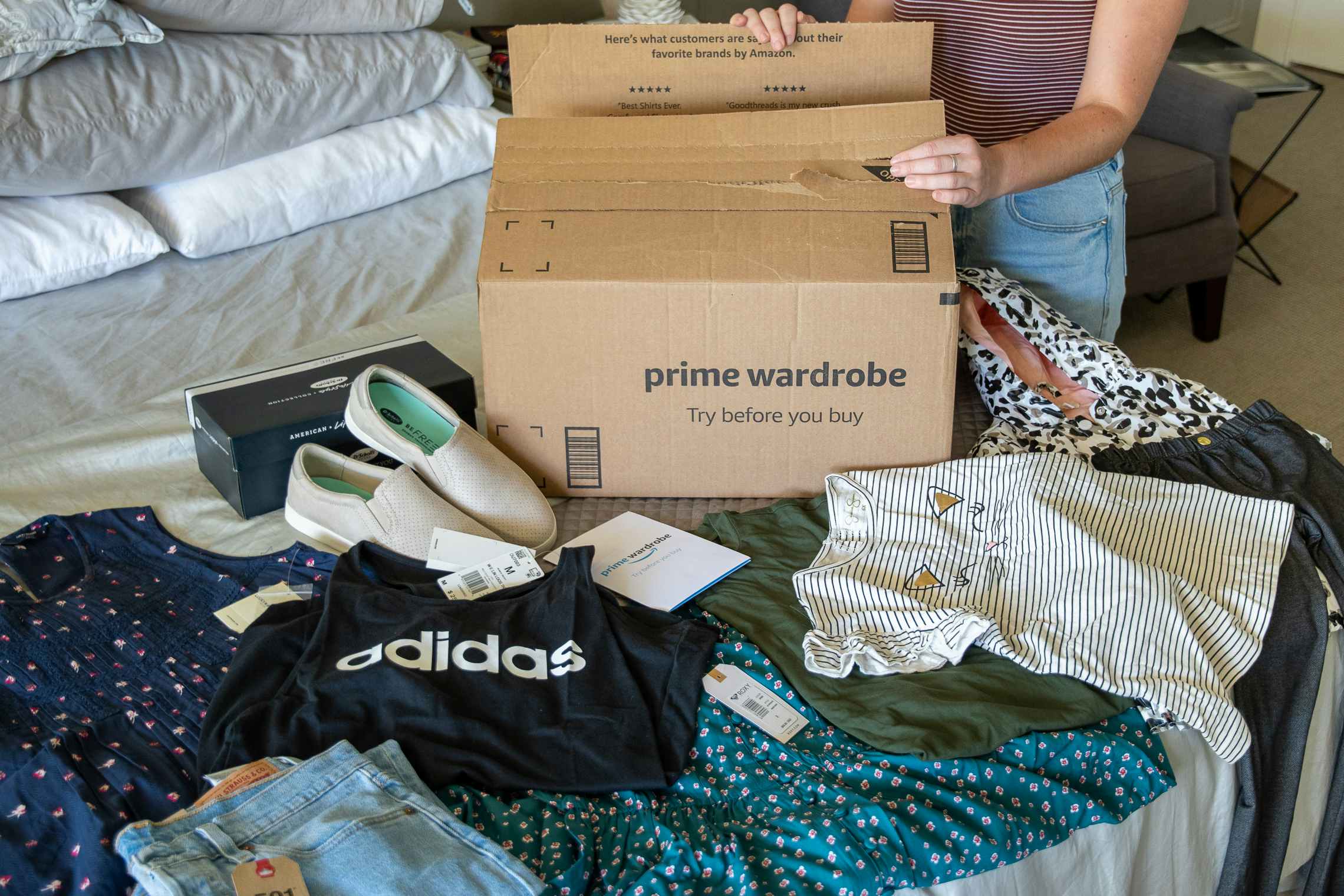 A woman unpacking an amazon prime wardrobe order from a box.