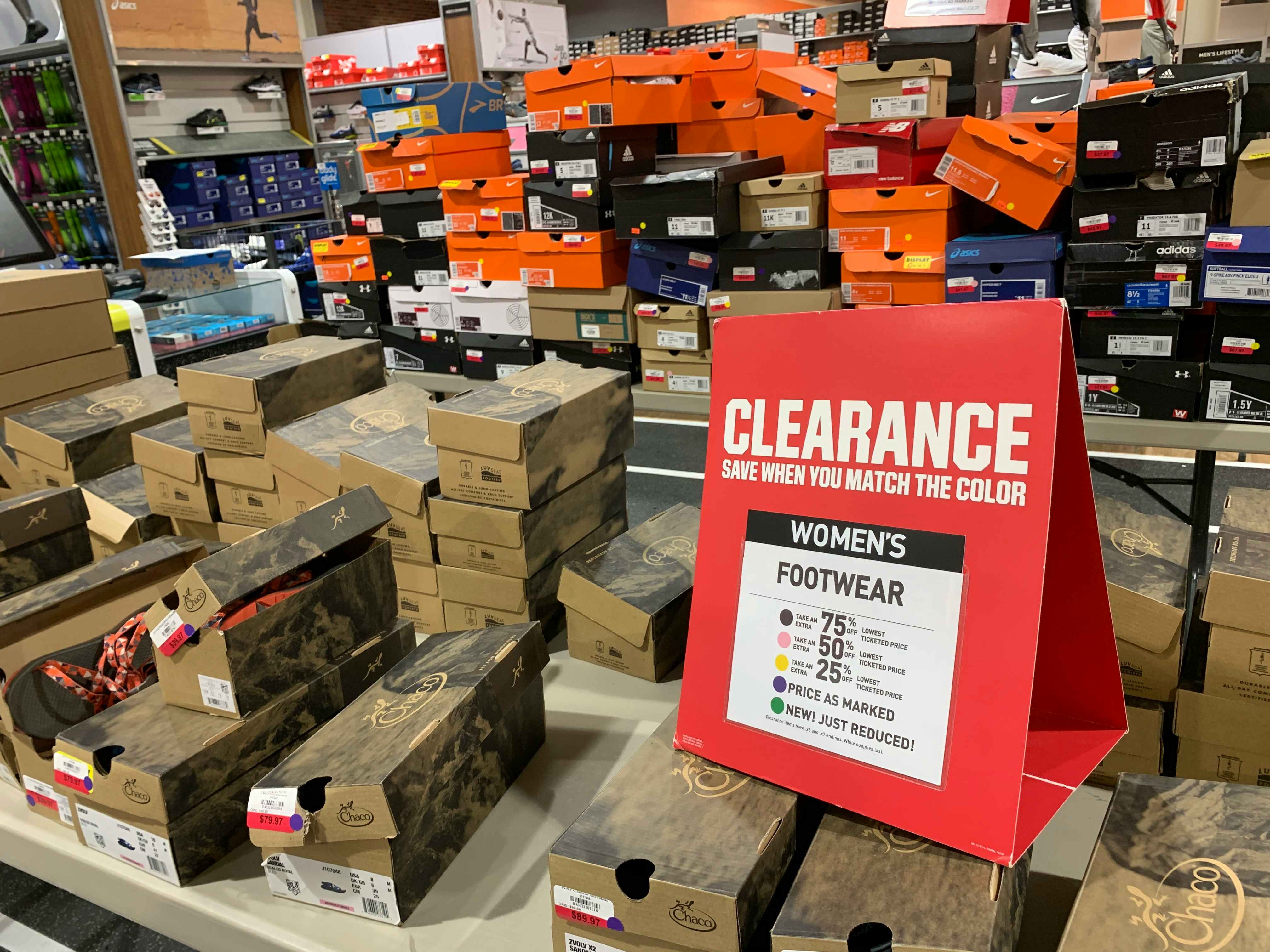 Two tables stacked with shoe boxes and a Clearance sign with information about the prices and clearance colors.