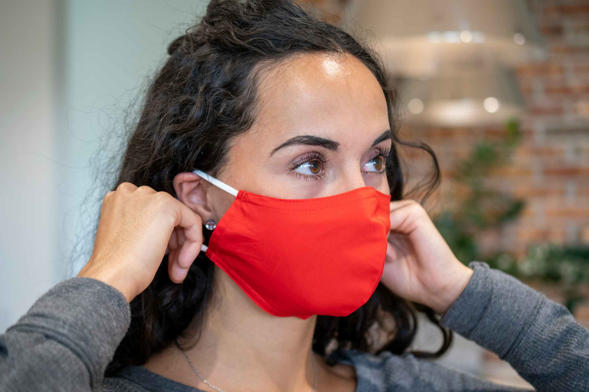 A woman putting on a fabric face mask.