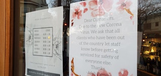 Signage on a hair salon door informing customers to notify employees if they've been out of country.