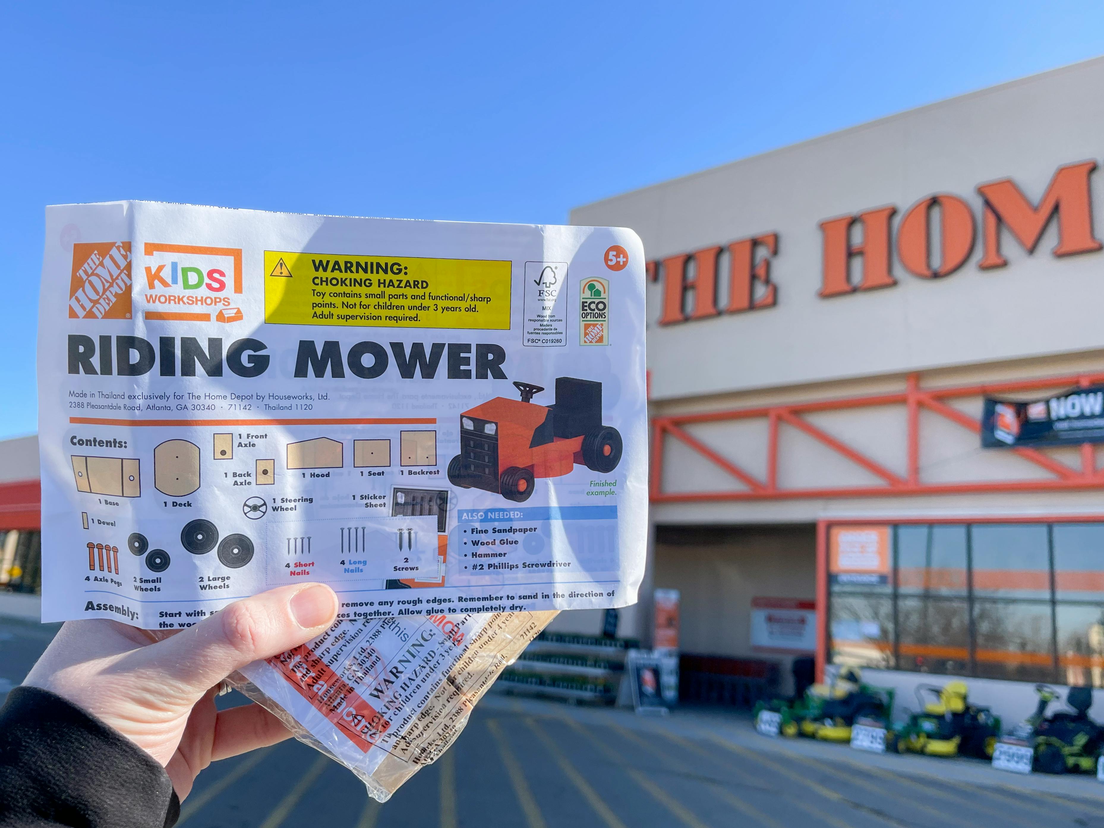 A Home Depot Kids Workshops Riding Mower kit held in front of the store