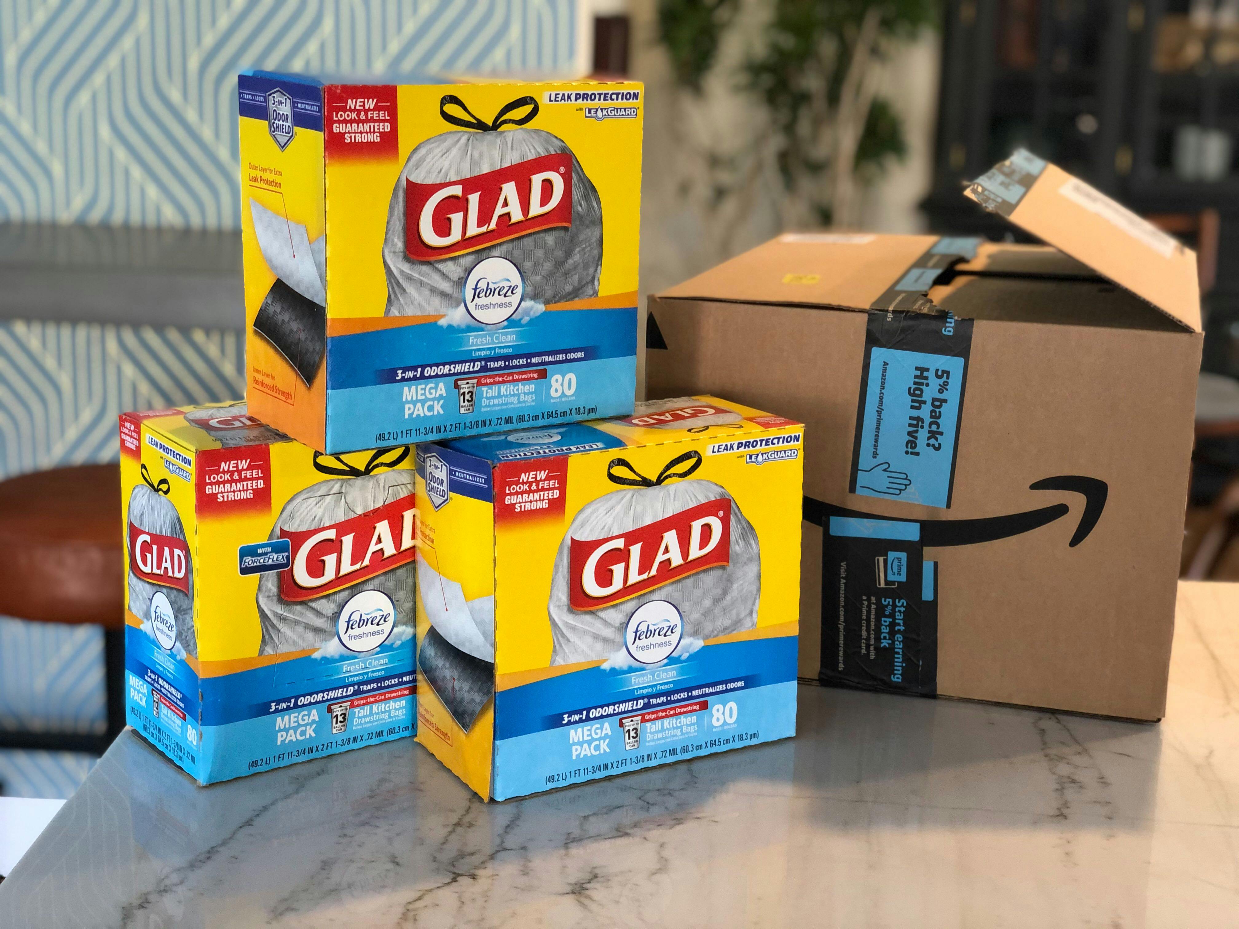 Three boxes of Glad trash bags stacked on a counter next to an Amazon box.
