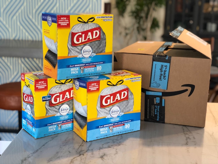 Three boxes of Glad trash bags stacked on a counter next to an Amazon box.
