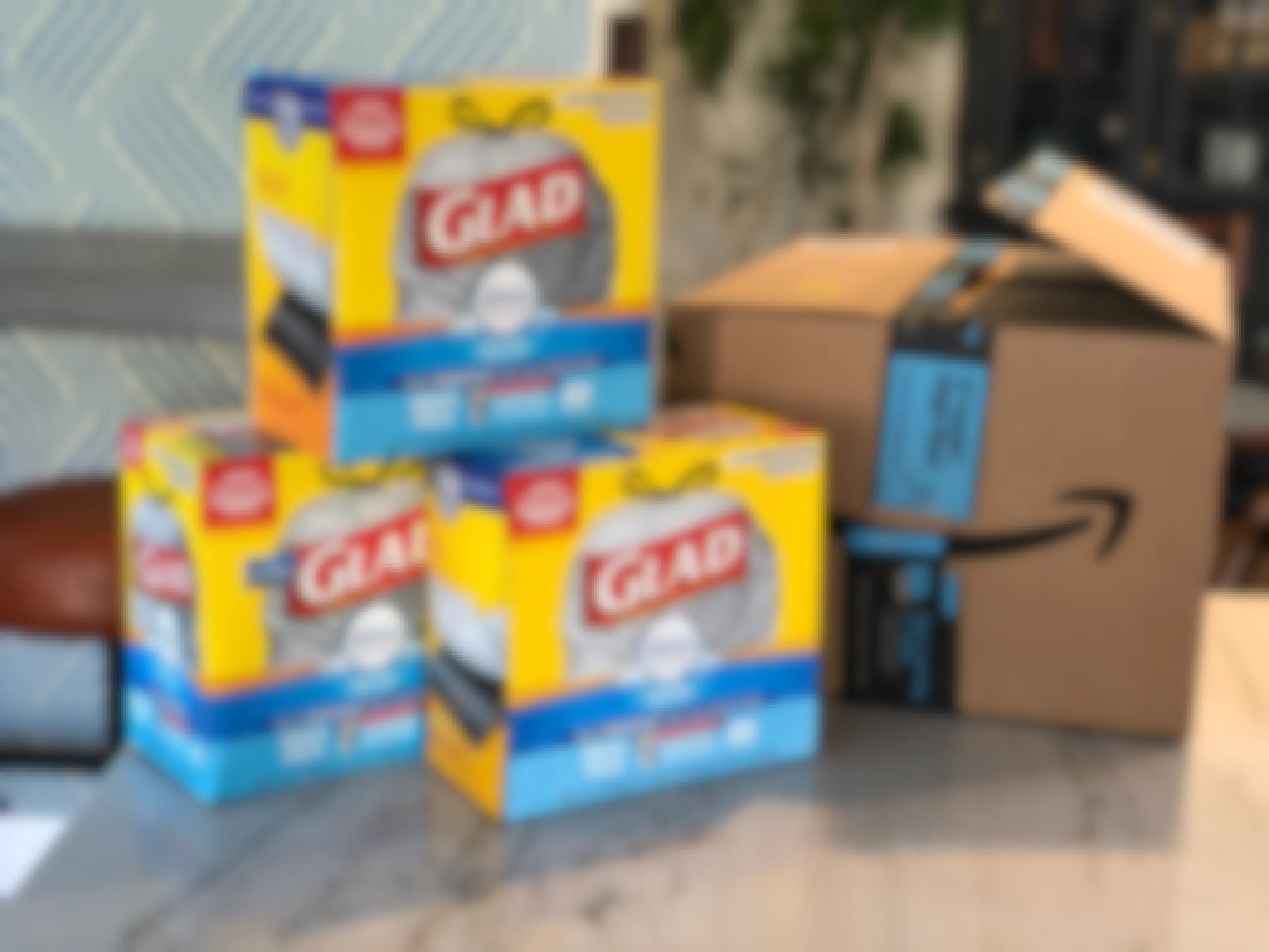 Three boxes of Glad trash bags stacked on a counter next to an Amazon box.