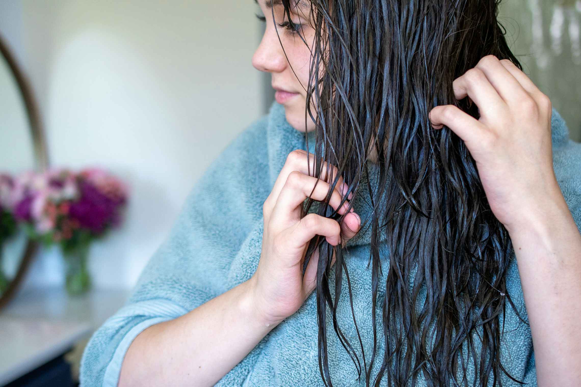 A woman combing through her wet hair with her fingers.