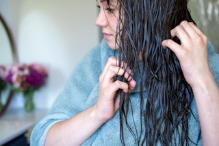 A woman combing through her wet hair with her fingers.