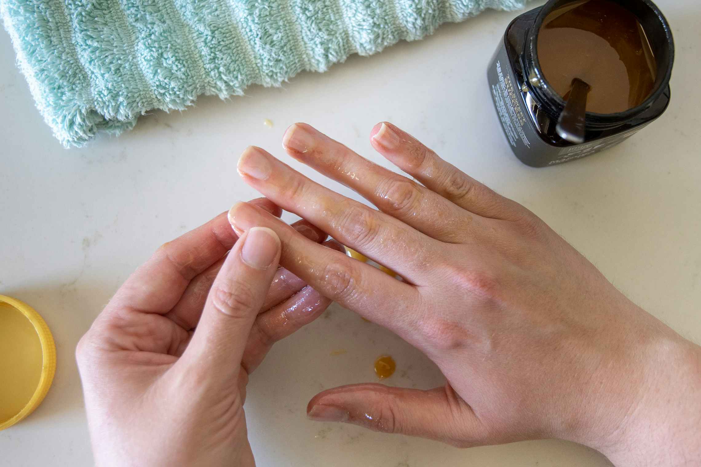 A woman massaging Manuka honey into her finger nails and cuticles.