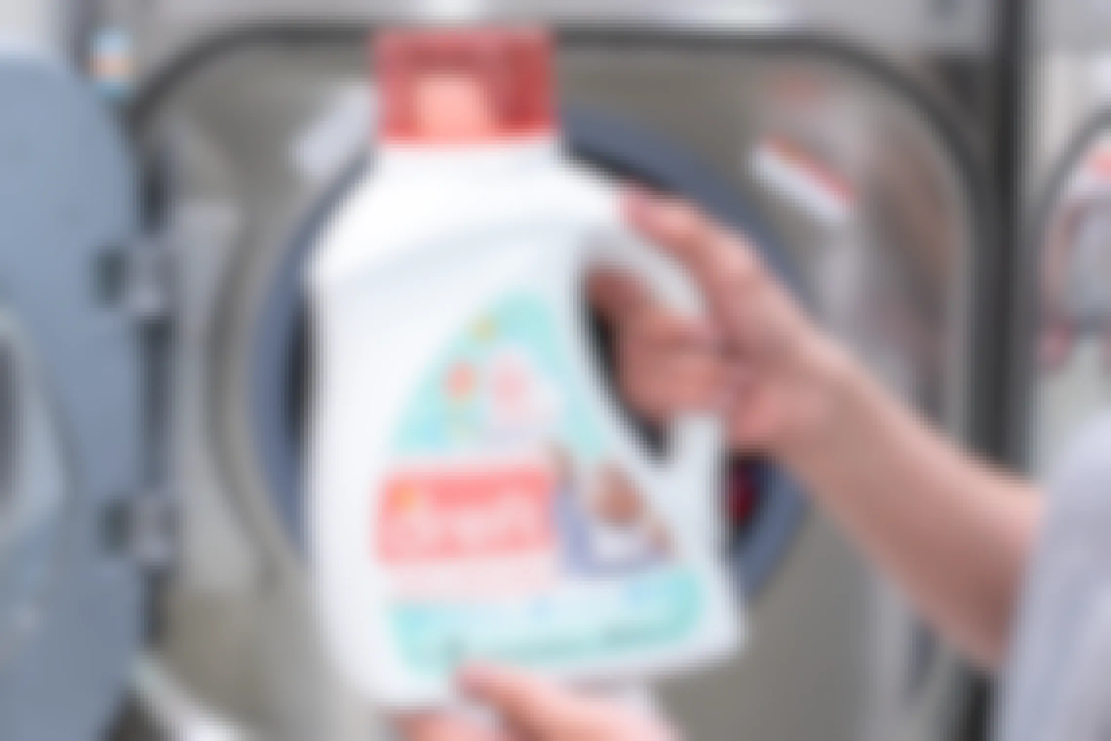 Dreft laundry detergent held in front of a washing machine.