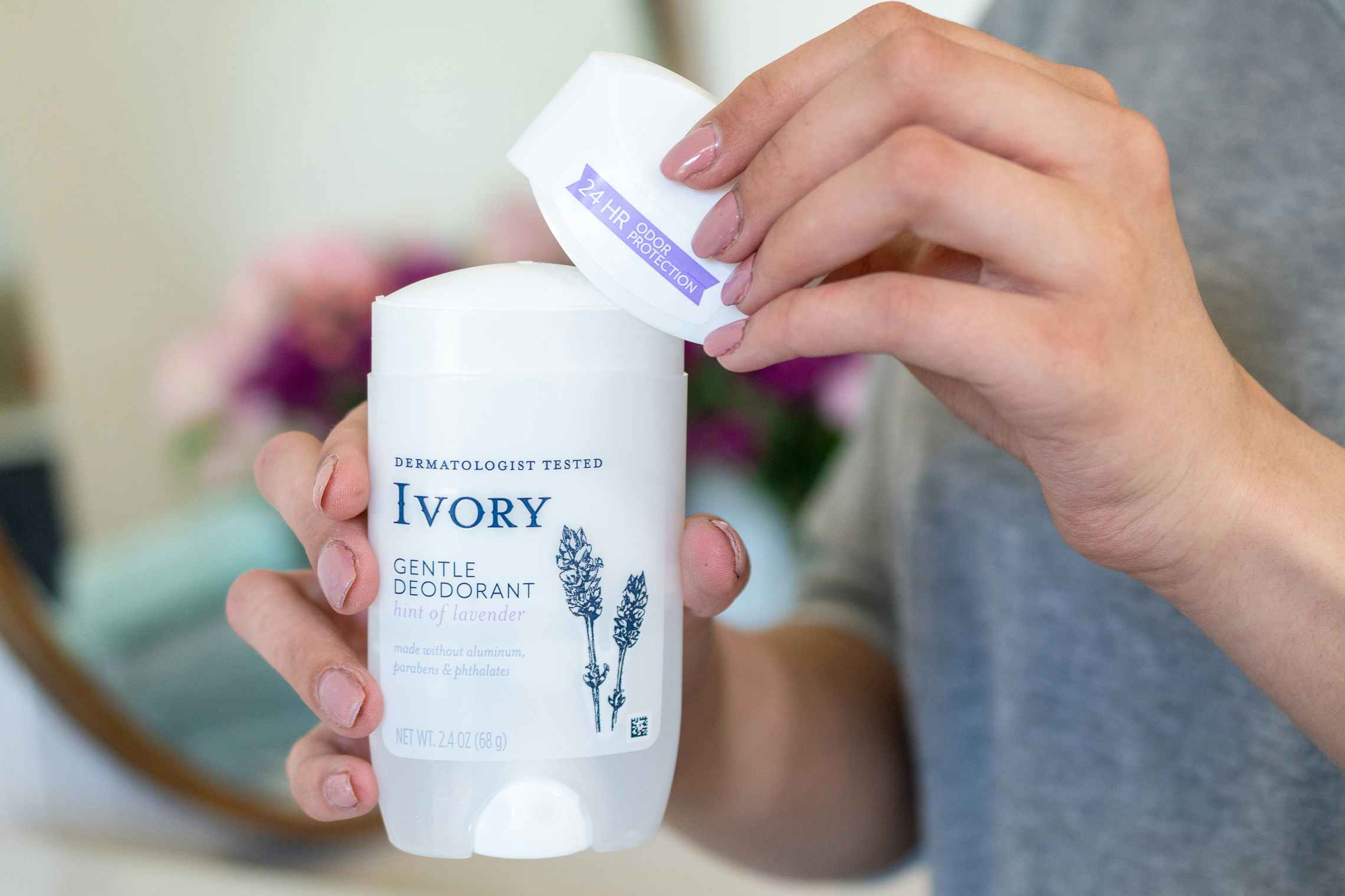 A woman taking the cap off Ivory deodorant.