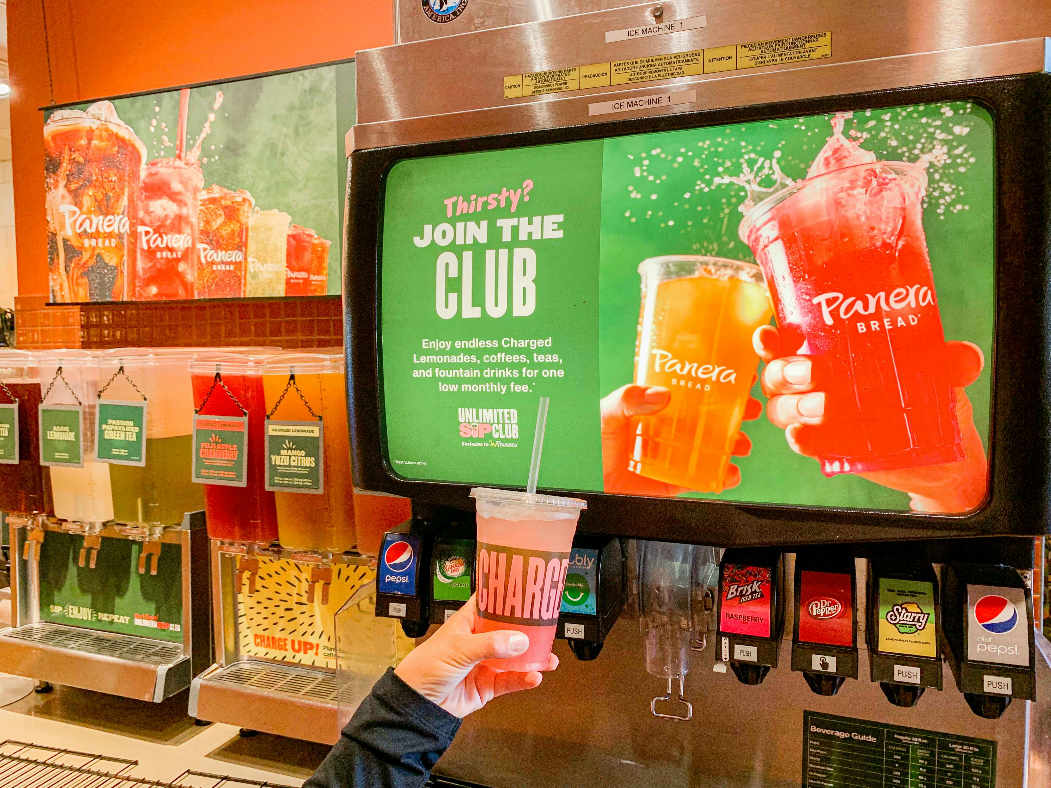 panera drink area with drink being held up in store