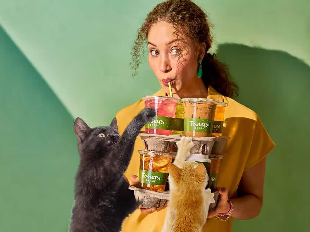 a woman drinking Panera beverages with pets on her lap, illustrating the partnership between PetSmart and Panera.