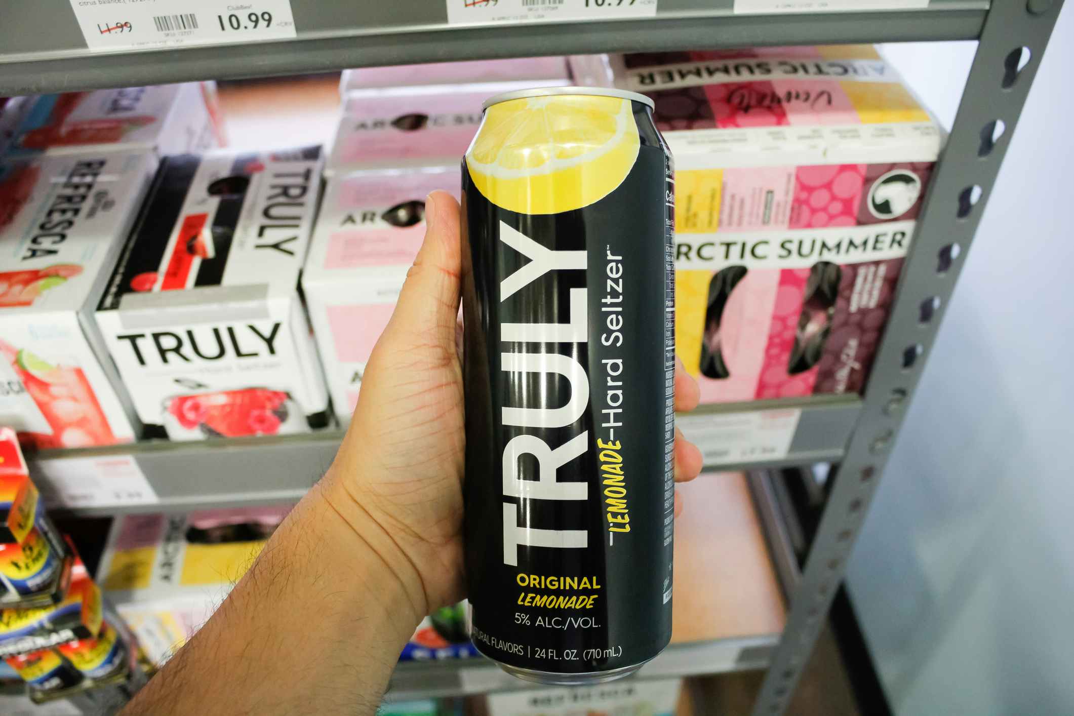 A hand holds a tall can of Truly Lemonade Hard Seltzer, on display at a local grocery store, in Los Angeles, California.