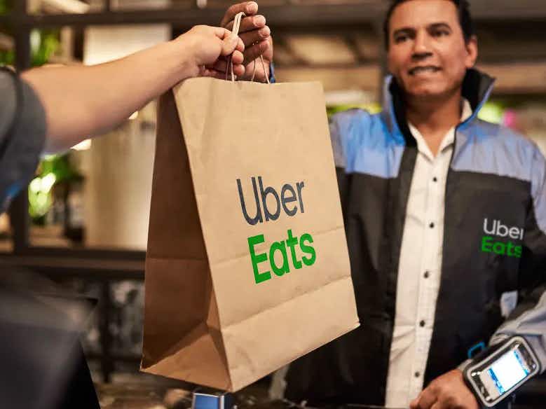 An Uber Eats delivery driver handing a bag to a customer