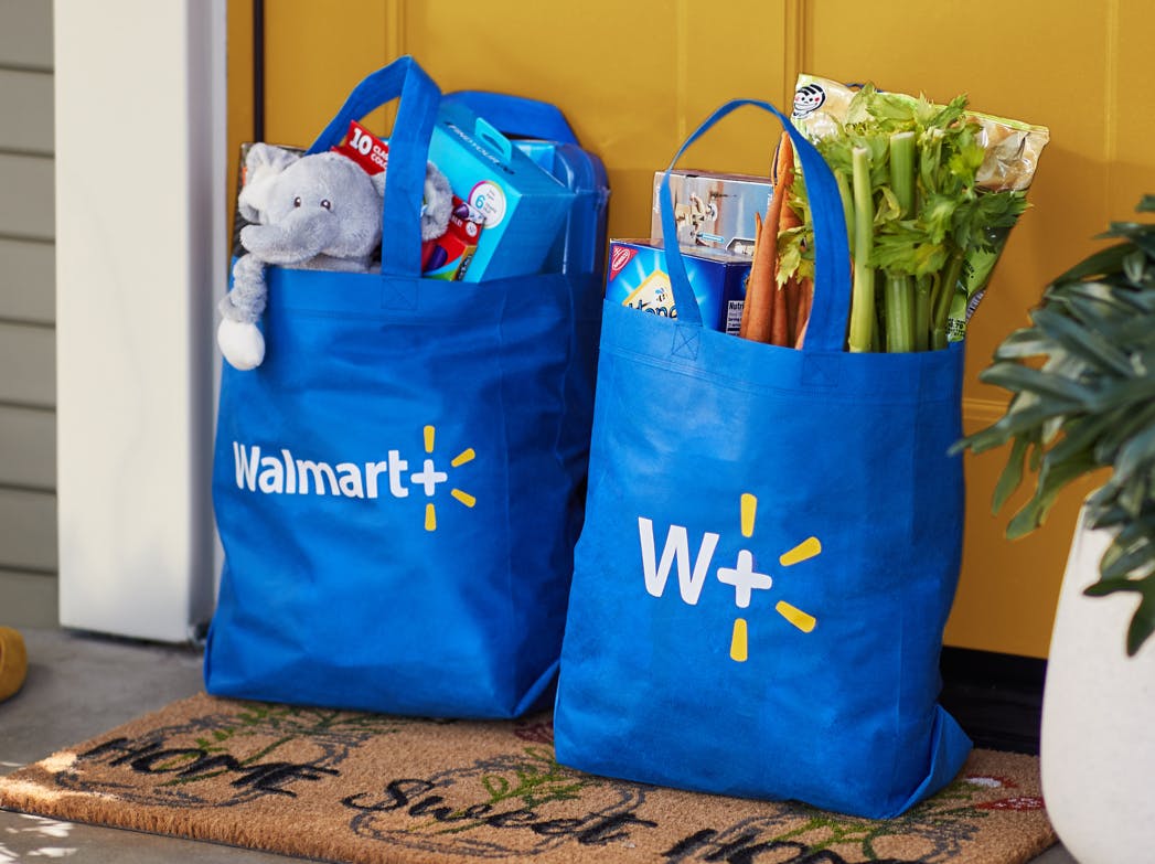 Two reusable Walmart Plus grocery bags filled with groceries sitting on a front porch.