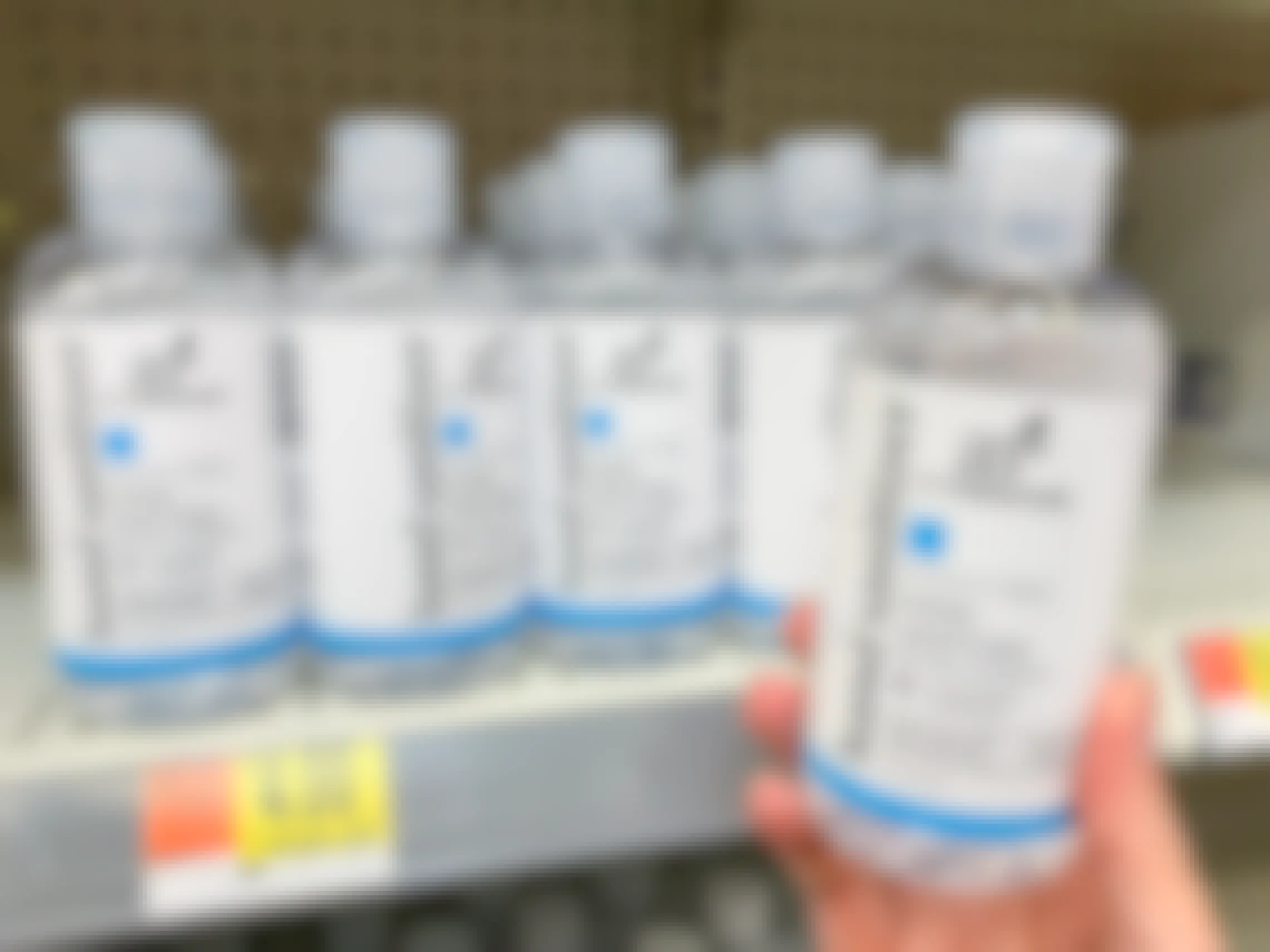 Hand sanitizer bottle held in front of a shelf full of the same product.