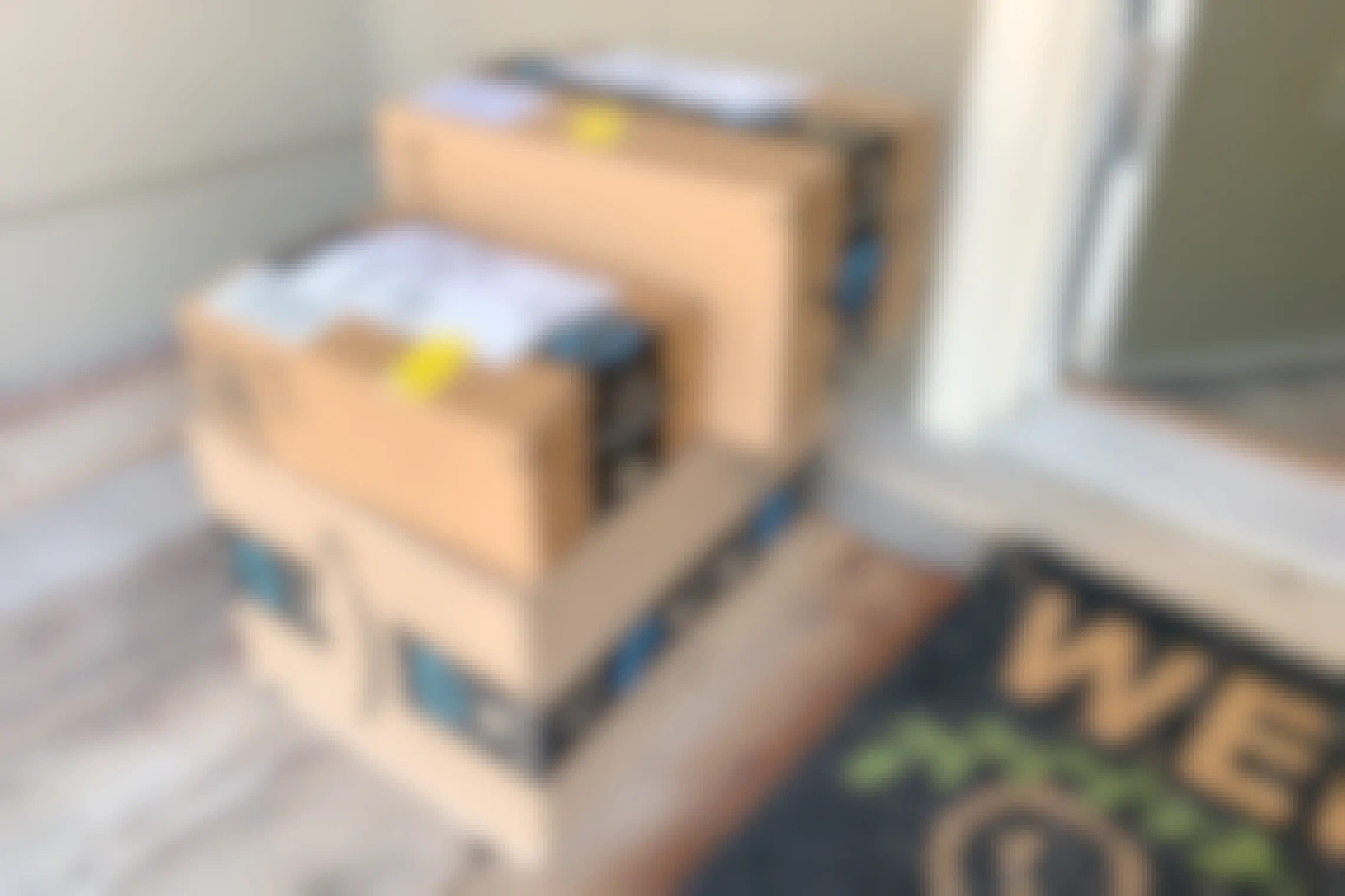 Three amazon prime boxes of varying sizes stacked on someone's doorstep