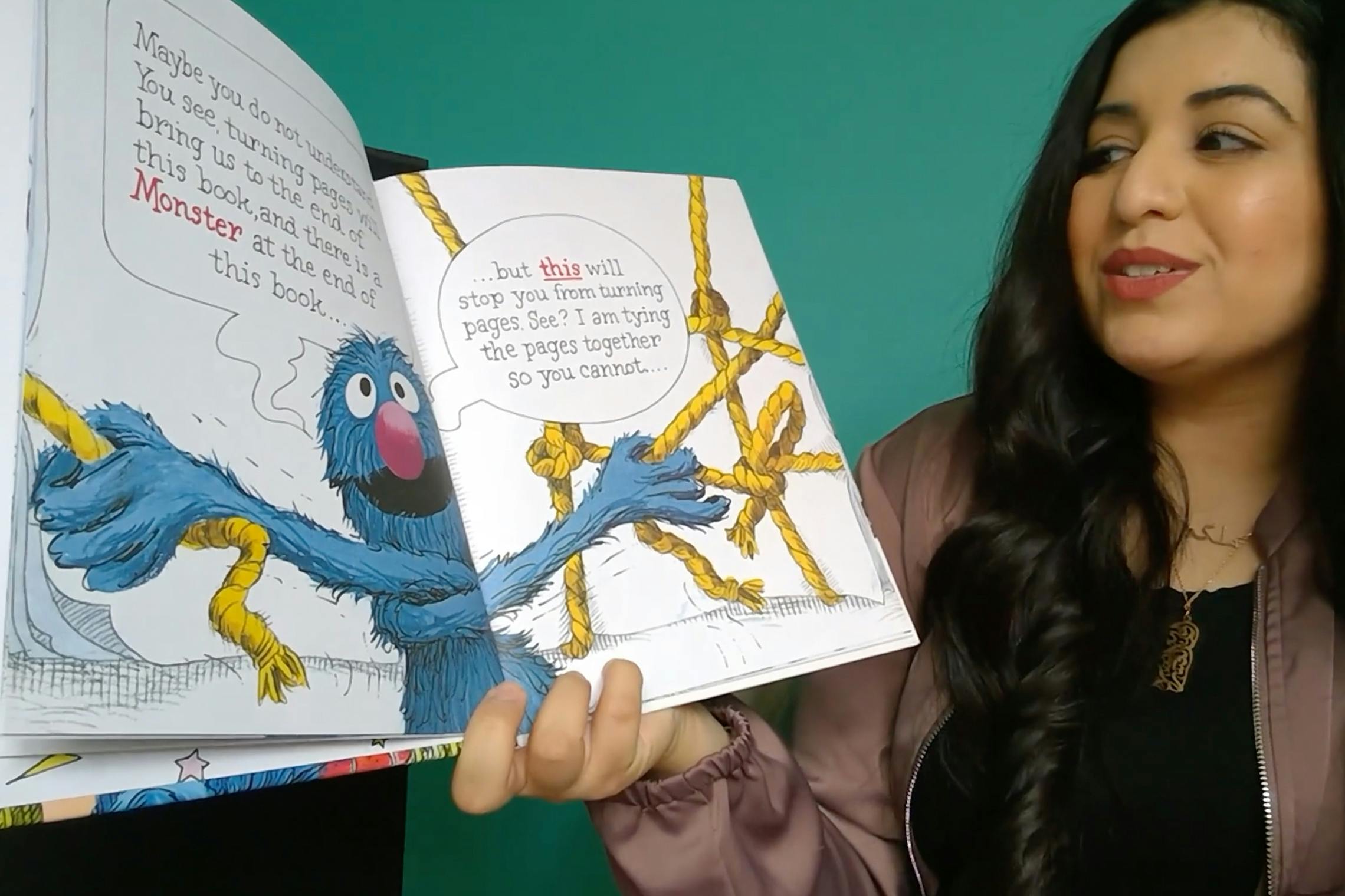 A woman reading a children's book, showing it to the camera.