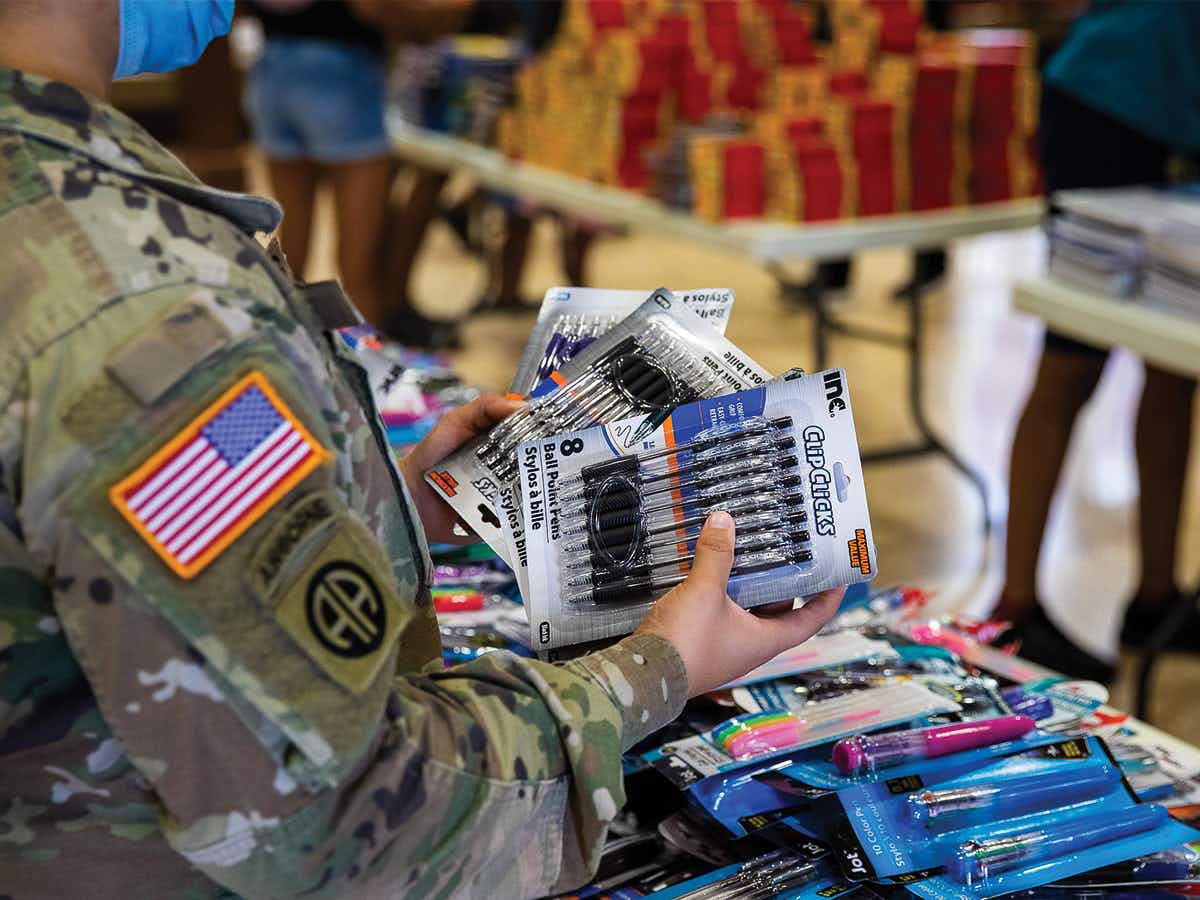 A person in military dress holding packs of pens